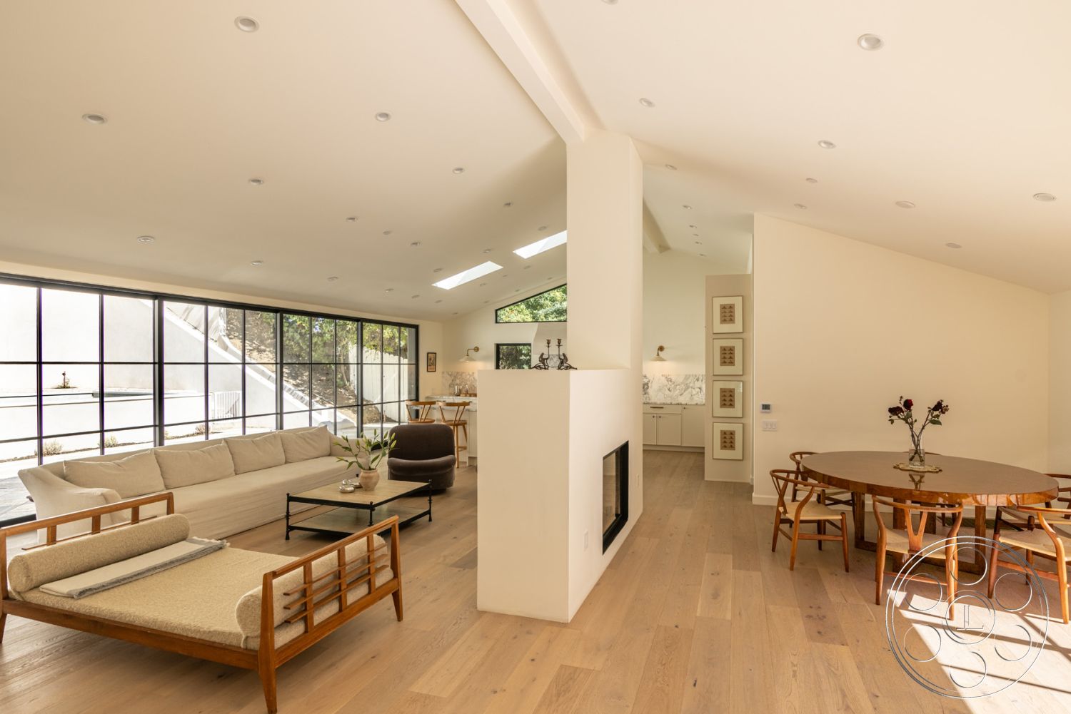 Modern Farmhouse 19 - interior neutral color palette, interior minimalist decor, interior hardwood living room floors, interior exposed wood ceiling beams, interior marble kitchen backsplash, interior floor-to-ceiling windows, interior minimalist coffee table, interior white painted walls, interior built-in kitchen cabinets, interior sectional sofa, interior sliding glass doors, interior vaulted living room ceiling, interior contemporary dining table, interior bright natural lighting, interior circular dining setting, interior modern fireplace feature, interior open plan layout