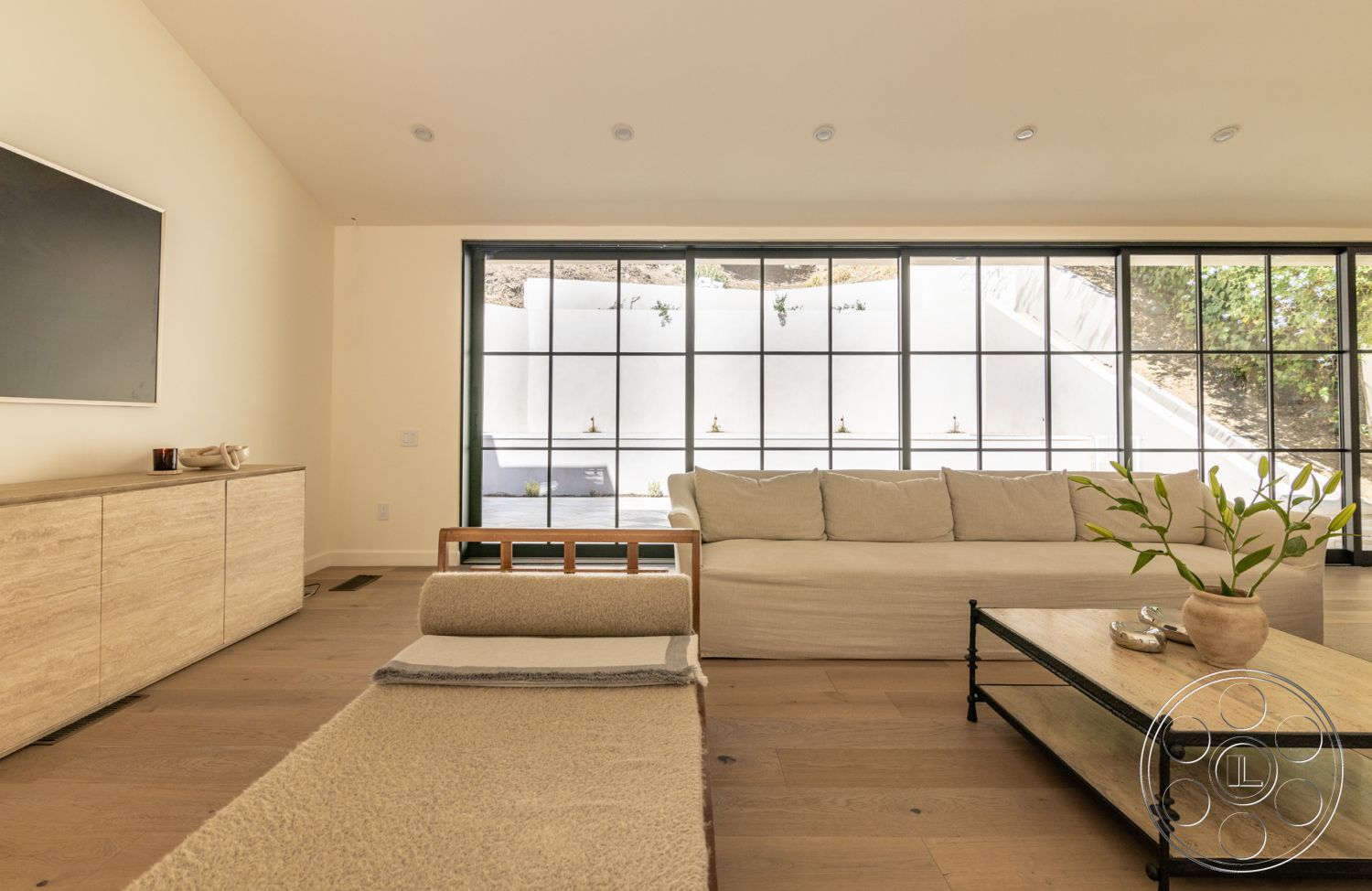 Modern Farmhouse 19 - interior hardwood living room floors, interior natural light-filled space, interior cozy seating area, interior rectangular coffee table, interior open layout design, interior modern minimalist aesthetic, interior beige textured wall, interior large black framed windows, interior minimalist wooden sideboard cabinet, interior organic cotton sofa, interior decorative ceramic pot, interior green plant accent