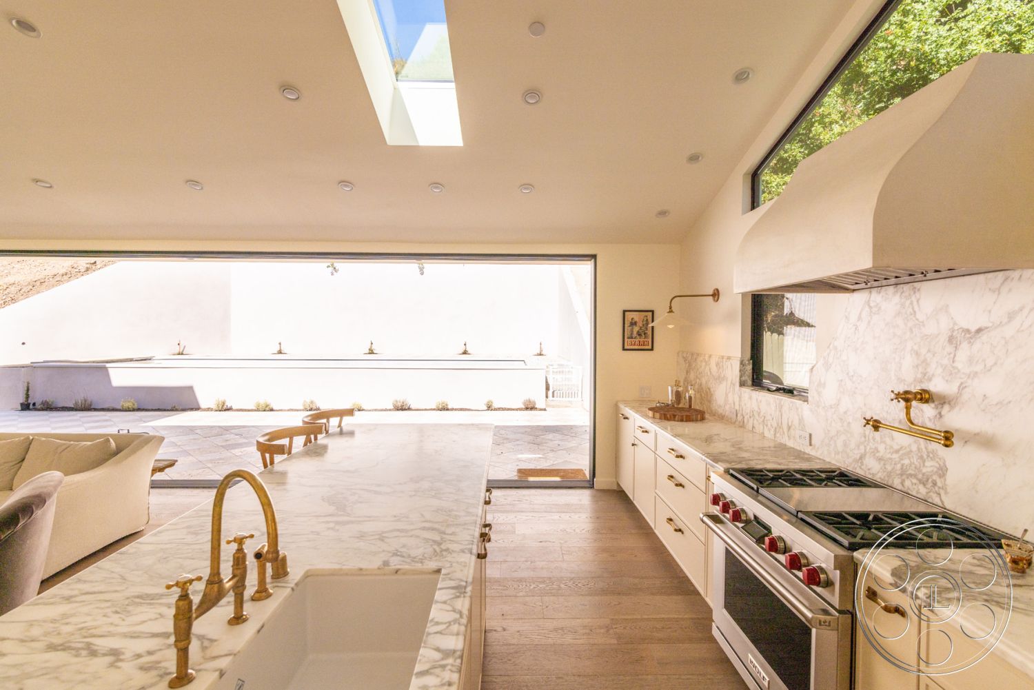 Modern Farmhouse 19 - interior open-concept layout, interior recessed lighting, exterior stone patio flooring, interior coffered ceiling details, interior marble kitchen countertops, interior hardwood kitchen floors, interior glass sliding doors, interior large windows for natural light, exterior minimalistic design, interior white cabinetry, exterior patio setting, interior stone backsplash, interior brass kitchen fixtures, exterior serene outdoor view, exterior smooth white stucco walls, interior contemporary kitchen appliances