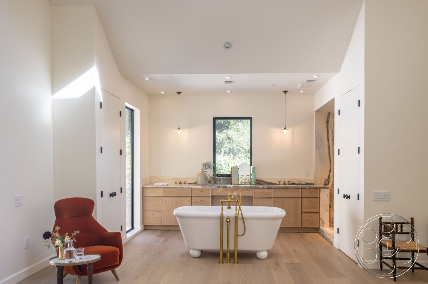 Modern Farmhouse 19 - neutral color palette, textured plaster walls, modern farmhouse aesthetic, modern cabinetry with clean lines, open-concept space, elegant bathroom design, white painted walls, freestanding soaking tub, natural light abundance, hardwood bathroom flooring, brass faucet fixtures, black hardware details, stone countertops with veining, floating vanity with wood cabinetry, large picture window with nature view, minimalist bathroom lighting fixtures, seating area with accent chair