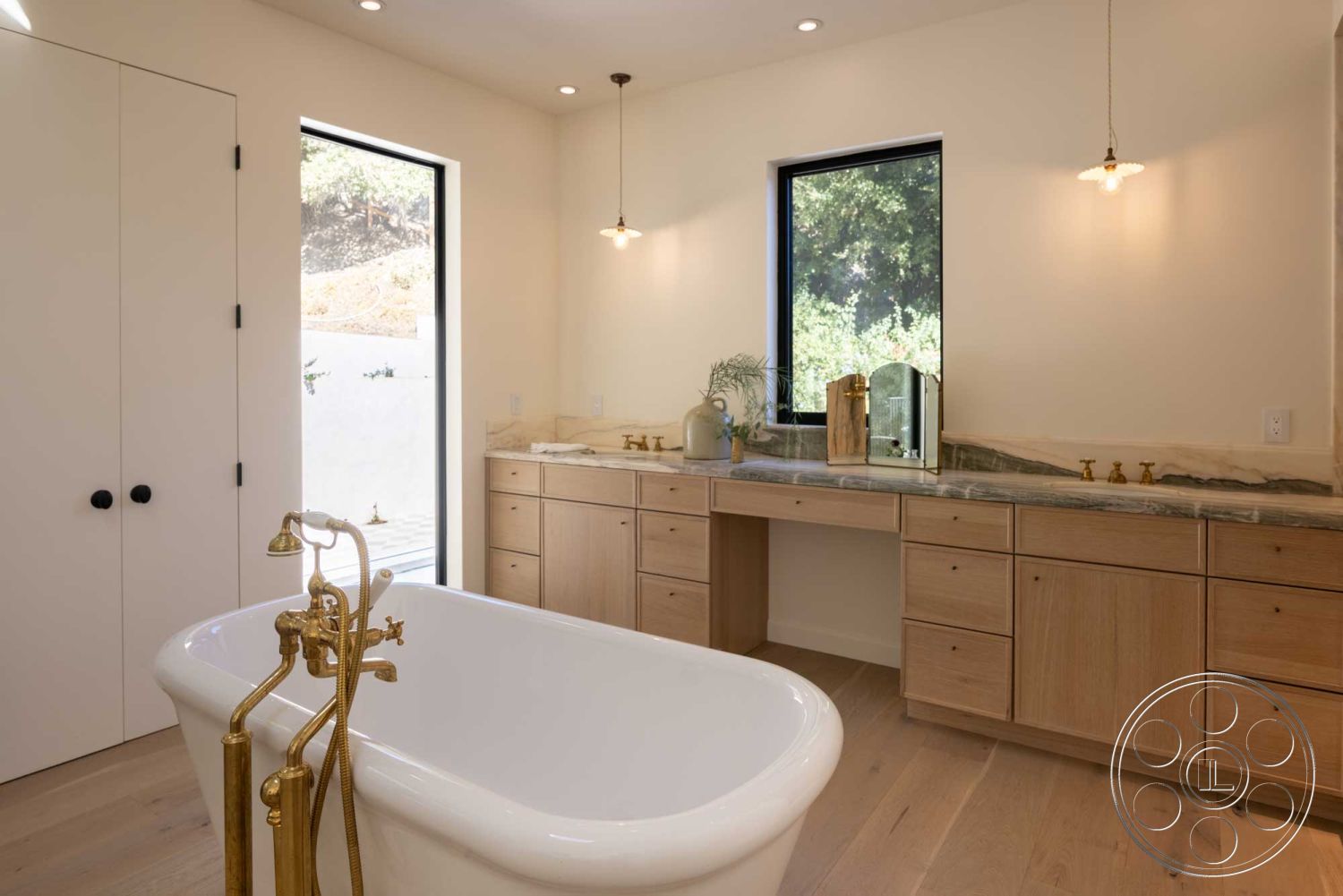 Modern Farmhouse 19 - minimalist design, open layout, modern design, natural wood flooring, marble countertop, soft ambient lighting, contemporary finishes, light oak cabinetry, neutral painted walls, interior bathroom, freestanding soaking tub, large windows with black frames, brass faucet fixtures, vanity mirror with brass accents, spacious bathroom