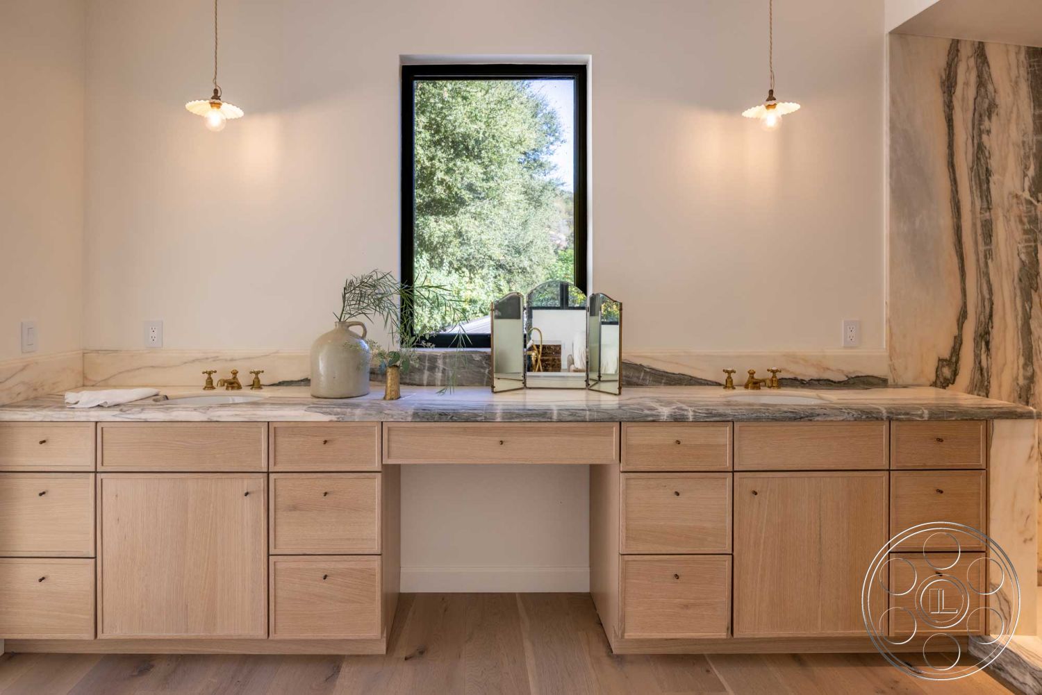 Modern Farmhouse 19 - clean lines, minimalist design, textured stone wall, light hardwood flooring, natural wood cabinetry, marble countertop, stylish decor elements, large window for natural light, functional space layout, interior bath space, brass faucet fixtures, neutral wall treatment, views of surrounding greenery, understated pendant lighting, integrated mirror