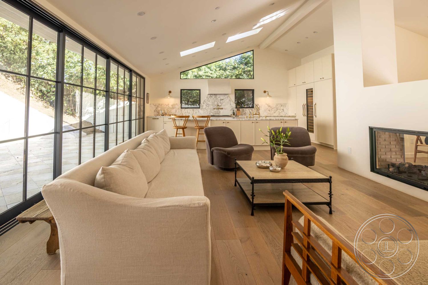 Modern Farmhouse 19 - interior vaulted ceiling, interior neutral color palette, interior hardwood living room floors, interior marble kitchen backsplash, interior minimalist dining area, interior stainless steel appliances, interior beige sectional sofa, interior glass sliding door, interior potted greenery accent, interior white cabinetry, interior pendant lighting, interior exposed brick fireplace wall, interior modern glass windows, interior sculptural coffee table, interior contemporary wood dining chairs, interior light-filled open floor plan, interior natural light flooding in