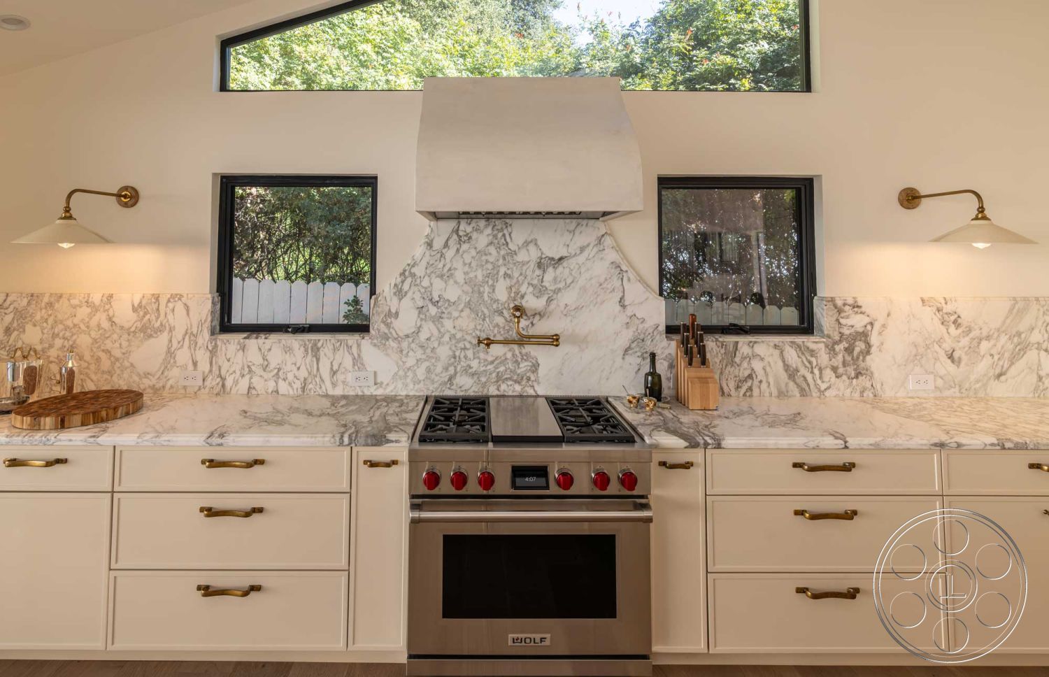 Modern Farmhouse 19 - minimalist aesthetic, marble countertop, soft ambient lighting, black framed windows, natural greenery view, natural light from large windows, luxurious materials, functional kitchen layout, modern kitchen design, marble kitchen backsplash, open concept interior, task lighting fixtures, white painted kitchen cabinets, kitchen workspace, brushed brass cabinet hardware, stainless steel range oven, wooden serving board, contemporary kitchen interior, elevated ceiling with angular roof, chef's kitchen with modern appliances