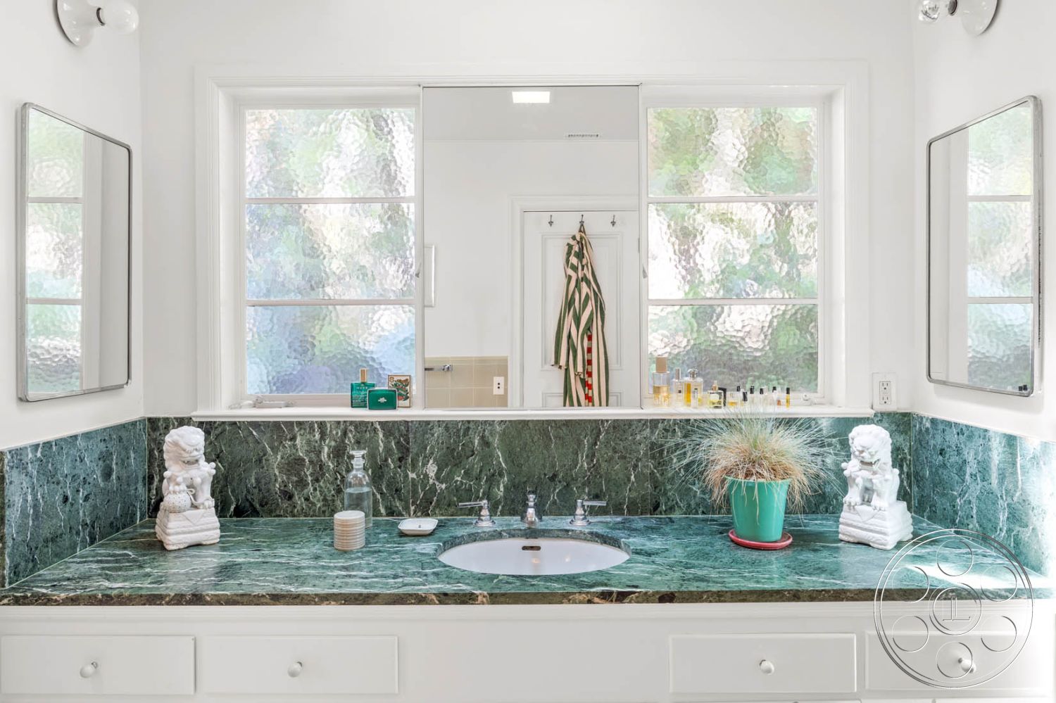 English 60 - exposed white painted walls, interior marble bathroom countertop, contemporary bathroom layout, modern bathroom mirrors, decorative lion statue, double sink vanity with contemporary faucets, textured glass window treatment, green marble backsplash, ceramic bathroom flooring, minimalist decor with white cabinetry, natural light-filled bathroom, stylish potted plant accent, bathroom storage organization