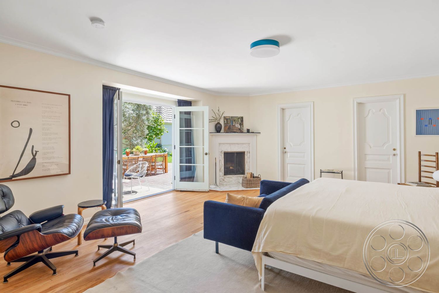 English 60 - textured area rug, minimalist design elements, interior bedroom, hardwood bedroom floors, neutral painted walls, marble fireplace surround, large glass patio doors, exposed ceiling with recessed lighting, white double French doors, simple contemporary furniture, modern armchair with wooden accents, painted wooden accent door, outdoor dining area view