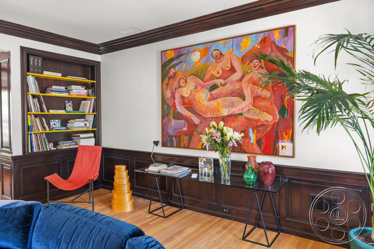 English 60 - neutral wall color, natural light from large windows, contemporary interior design, glass top coffee table, dark wood paneling walls, open interior layout, exposed wood crown molding, colorful abstract wall art, urban living space, home library nook, hardwood living room floor, modern accent chair, bookshelf with colorful accents, indoor tropical plants, decorative vases on table