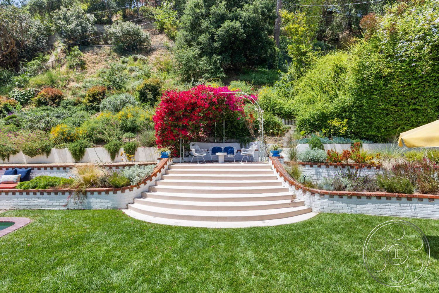 English 60 - exterior, surrounding greenery, concrete steps, outdoor living space, flowering shrubs, garden pathway, mountain backdrop, brick border, green grass lawn, multi-level terrace, decorative stone accents, urban hillside setting, paved patio area, bougainvillea plants, curved landscaping walls, wooden outdoor seating area