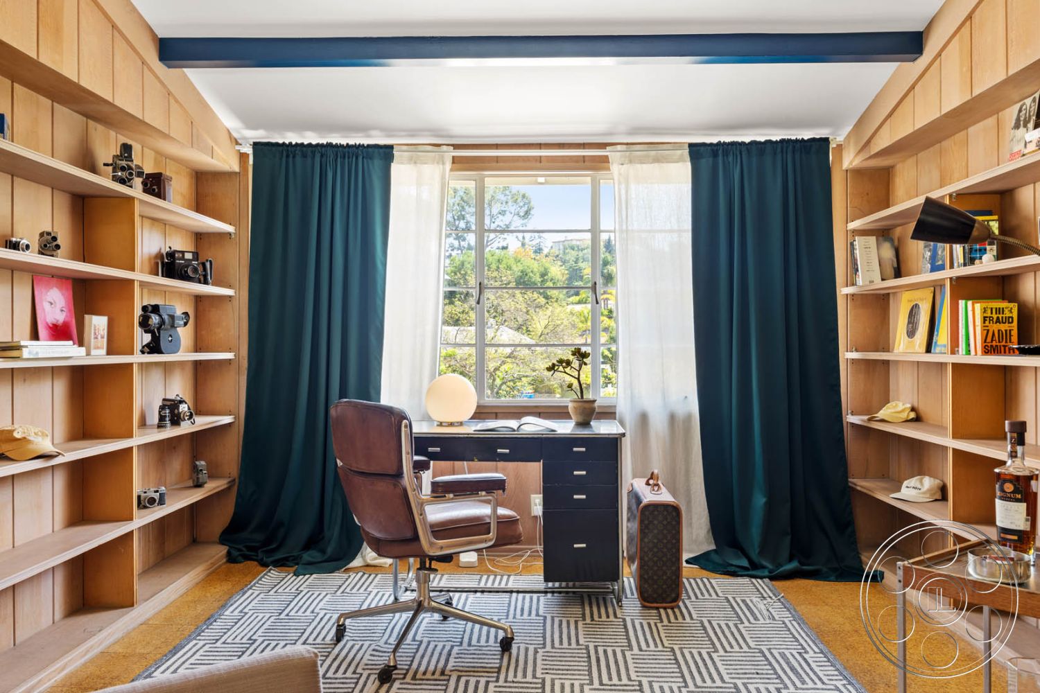 English 60 - neutral color palette, geometric area rug, soft natural lighting, green velvet curtains, textured carpet flooring, built-in wooden shelves, interior office space, wood paneling accent wall, modern ergonomic office chair, metal desk with drawers, large double-hung window, industrial-style desk lamp, decorative vintage cameras, vintage photographic prints, lively plant decor