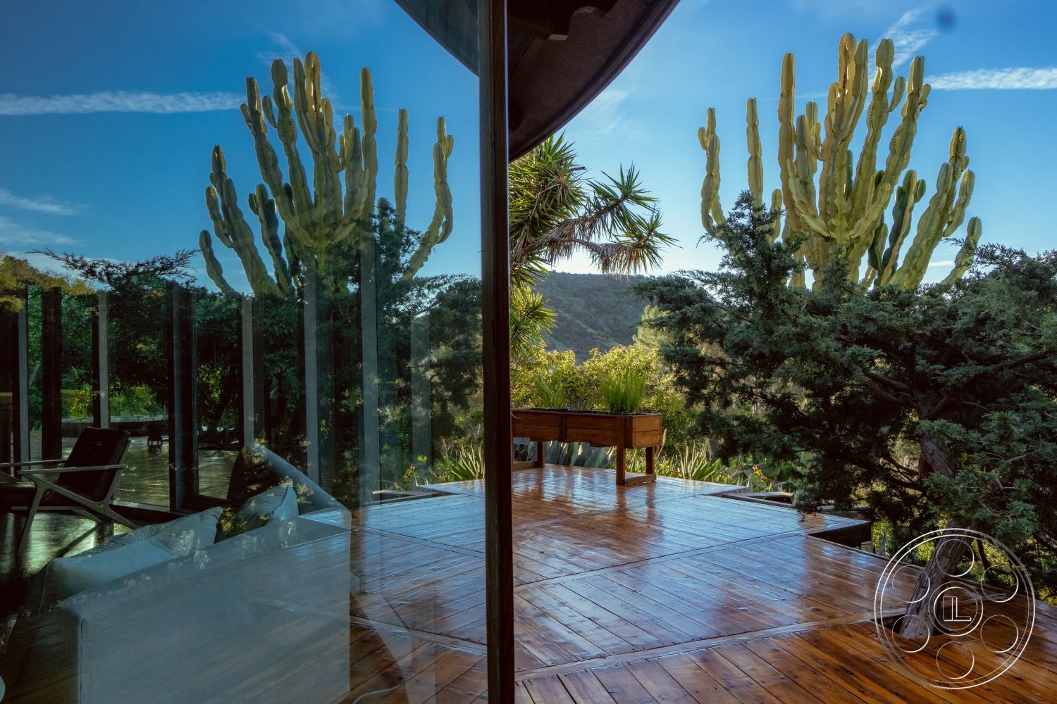 Pad 90210 - interior wooden deck flooring, interior sleek modern design, interior open concept living area, interior minimalist furniture, exterior landscaped garden setting, exterior glass sliding doors, interior seamless indoor-outdoor transition, exterior large glass windows, exterior panoramic mountain view, exterior natural light, exterior natural wood accents, exterior tropical plant landscape, exterior surrounding greenery
