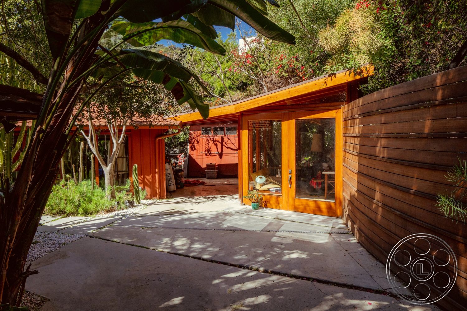 Pad 90210 - contemporary architectural style, exterior concrete patio floor, exterior landscaped garden setting, exterior glass sliding doors, exterior natural stone pathway, exterior tropical plant accents, exterior built-in planters, exterior wooden slat fence, exterior red-painted wood siding, exterior angled roof design