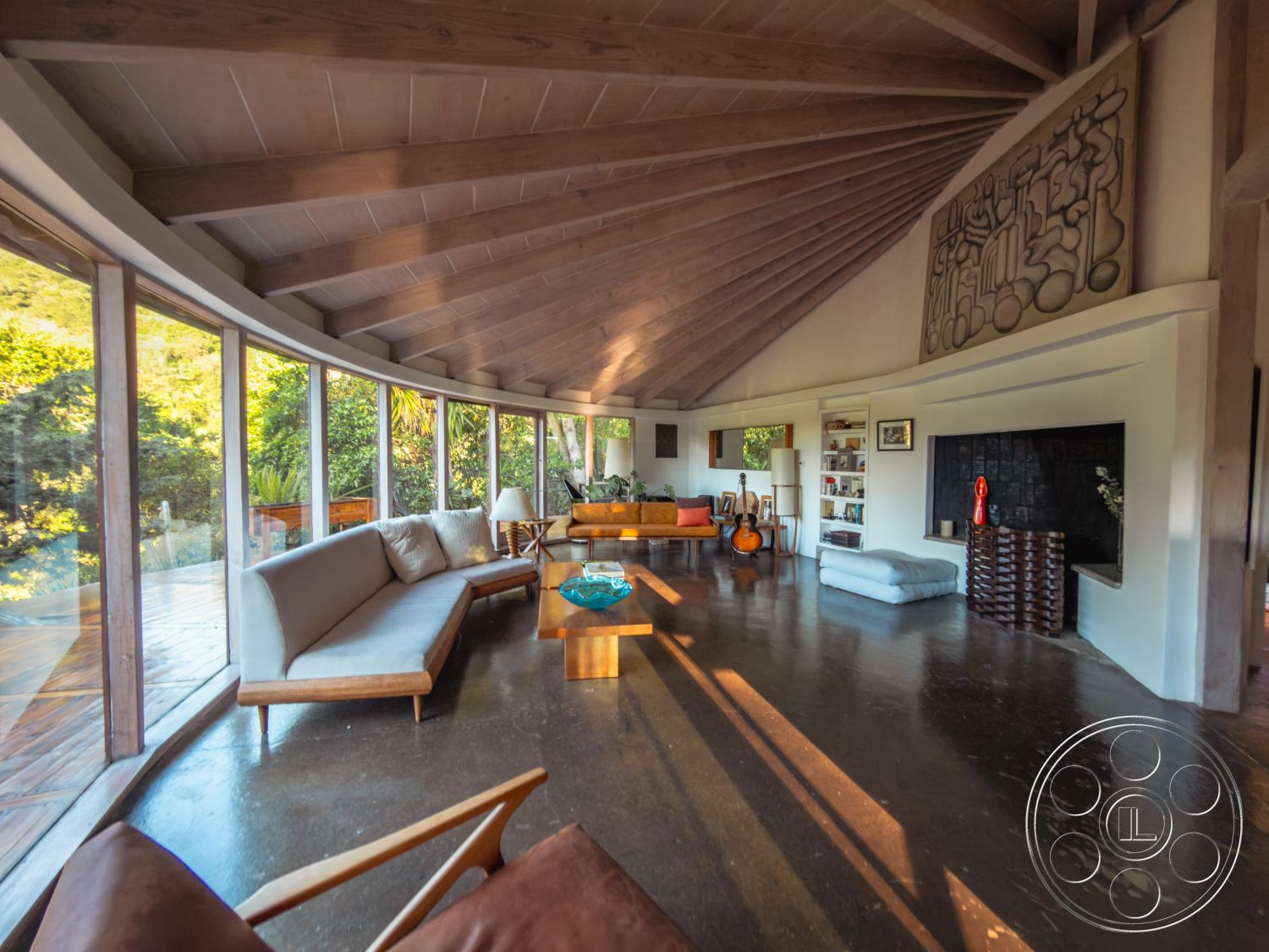 Pad 90210 - exposed wood ceiling beams interior, open concept living space interior, modern minimalist furniture interior, geometric wall art interior, earthy color palette interior, curved wall of glass windows interior, concrete polished flooring interior, natural light living room interior, wood accent furniture interior, wooden deck patio exterior, lush green garden view exterior, floating coffee table interior, compact built-in shelving interior, soft textile seating interior