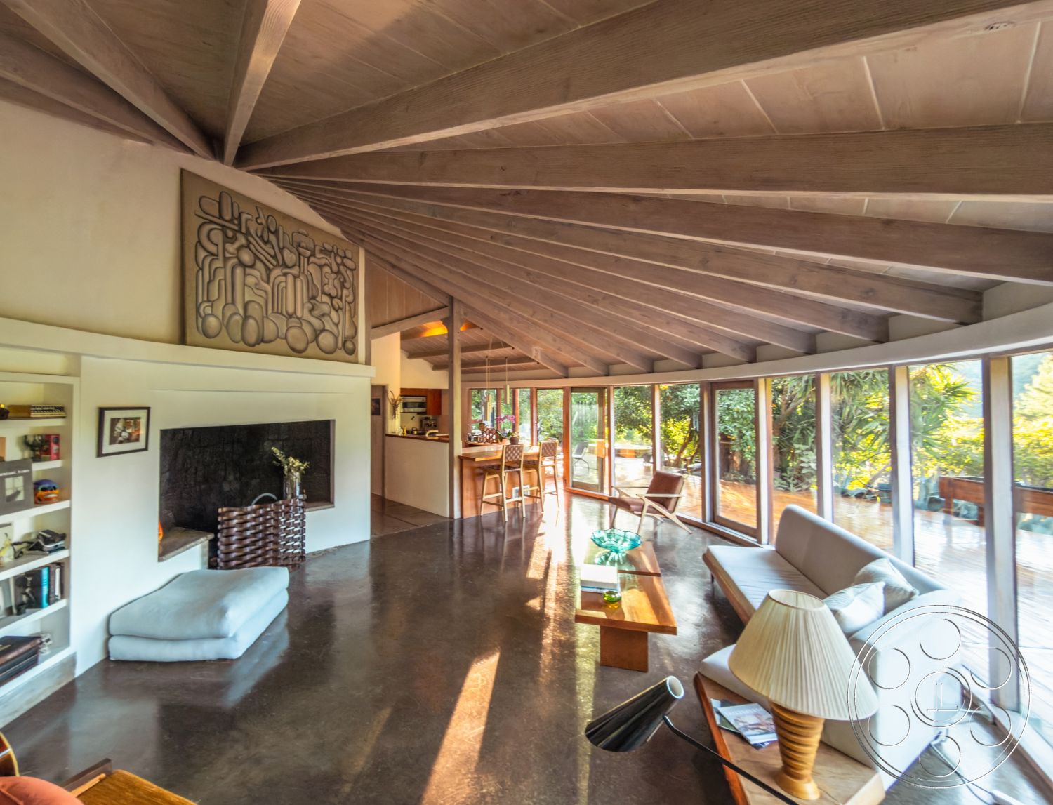 Pad 90210 - minimalist decor, textured wall art, wooden coffee table, concrete flooring, cozy seating area, large glass windows, greenery view, built-in shelving, bright and airy atmosphere, sleek furniture, curved walls, mid-century modern design, exposed wood ceiling beams, natural light interior, open concept living area, modern fireplace surround, outdoor patio access, functional home layout, wraparound deck, integrated kitchen space