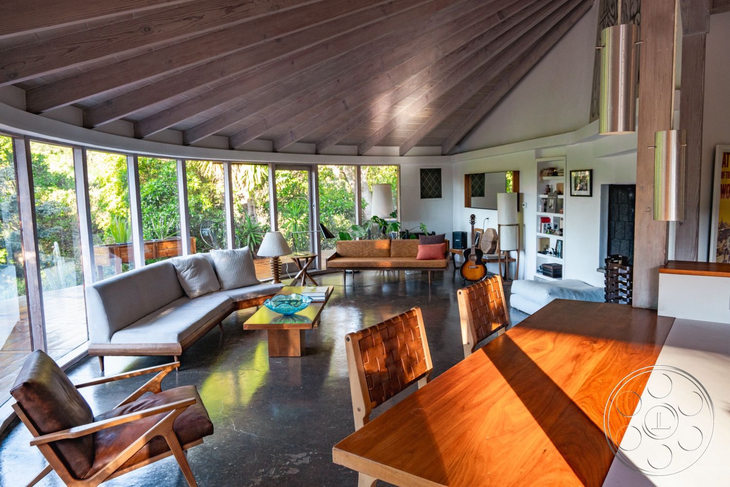 Pad 90210 - minimalist decor, natural light, indoor plants, open floor plan, light and airy atmosphere, polished concrete flooring, modern light fixtures, cozy seating area, wooden dining table, sliding glass doors, interior space, mid-century modern furniture, oval coffee table, exposed wood ceiling beams, white painted walls, built-in shelving unit, angular wooden ceiling, glass windows with garden view, leather accent chairs, integrated living space