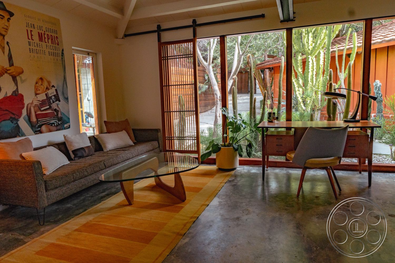 Pad 90210 - natural light, textured area rug, decorative pillows, exposed beam ceiling, modern coffee table, metal desk lamp, framed wall art, mid-century modern furniture, glass wall partitions, contemporary office space, concrete floor finish, open interior layout, interior living area, brightly lit workspace, cactus garden view, bamboo shade screens, wooden desk with drawers, indoor plant display, plush sofa with cushions, minimalistic design aesthetic