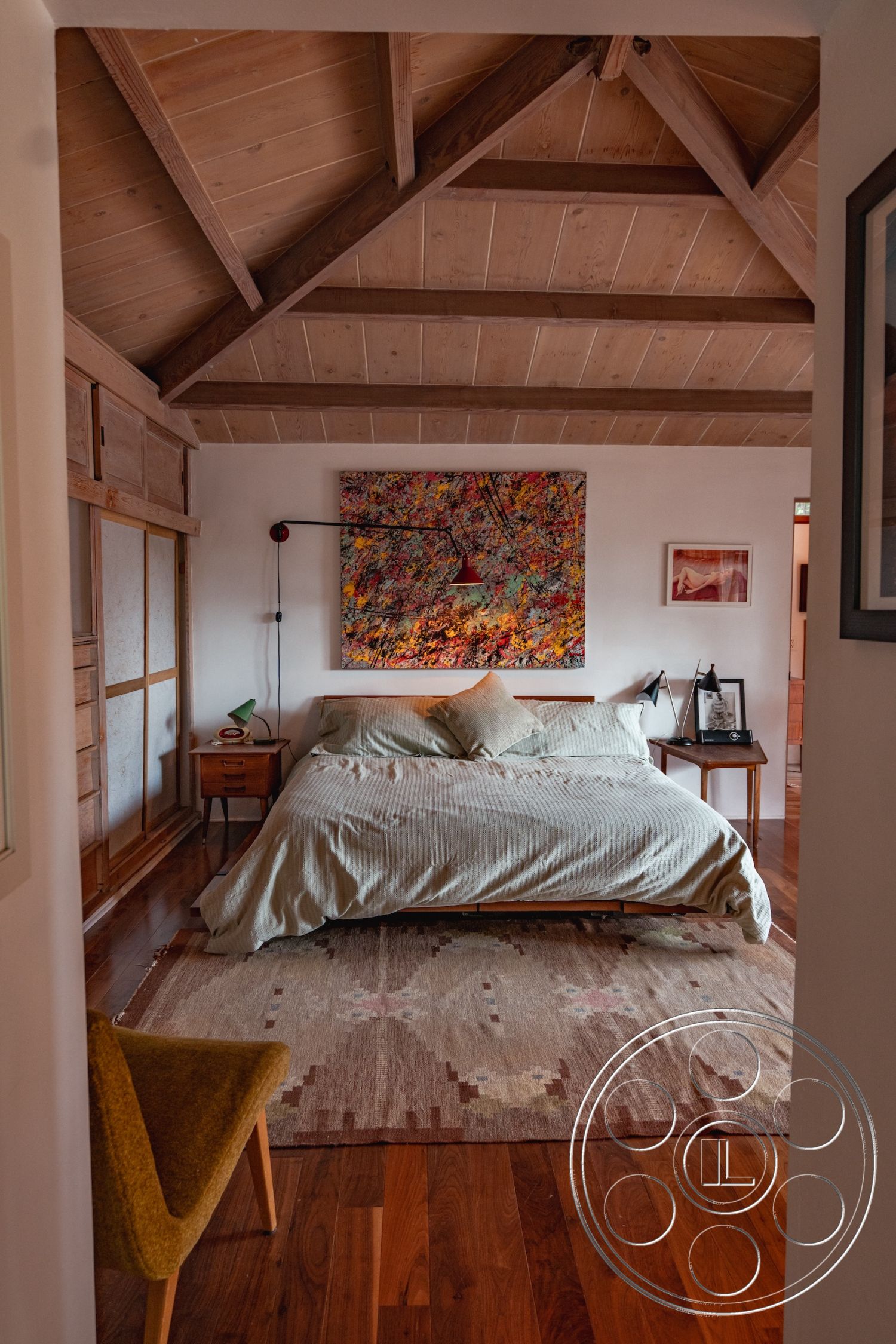 Pad 90210 - minimalist decor, contemporary style, textured wall art, cozy atmosphere, functional layout, vaulted ceiling, furniture arrangement, soft natural lighting, plush area rug, wooden nightstands, exposed wood ceiling beams, interior bedroom, hardwood bedroom floors, earth-toned bedding, accented wall