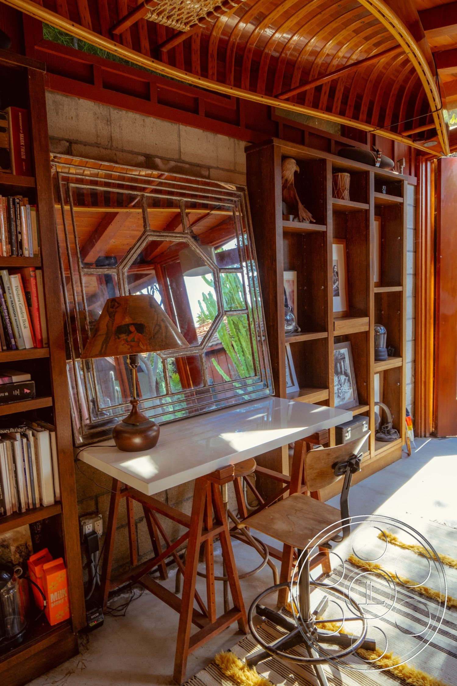 Pad 90210 - natural light, textured area rug, artistic wall art, bright and airy atmosphere, wooden shelving unit, contemporary interior design, minimalist workspace, exposed concrete block walls, open shelving design, plywood curved ceiling, white marble desk surface, hardwood bookshelf, mid-century modern desk chair, geometric mirror, rustic décor accents