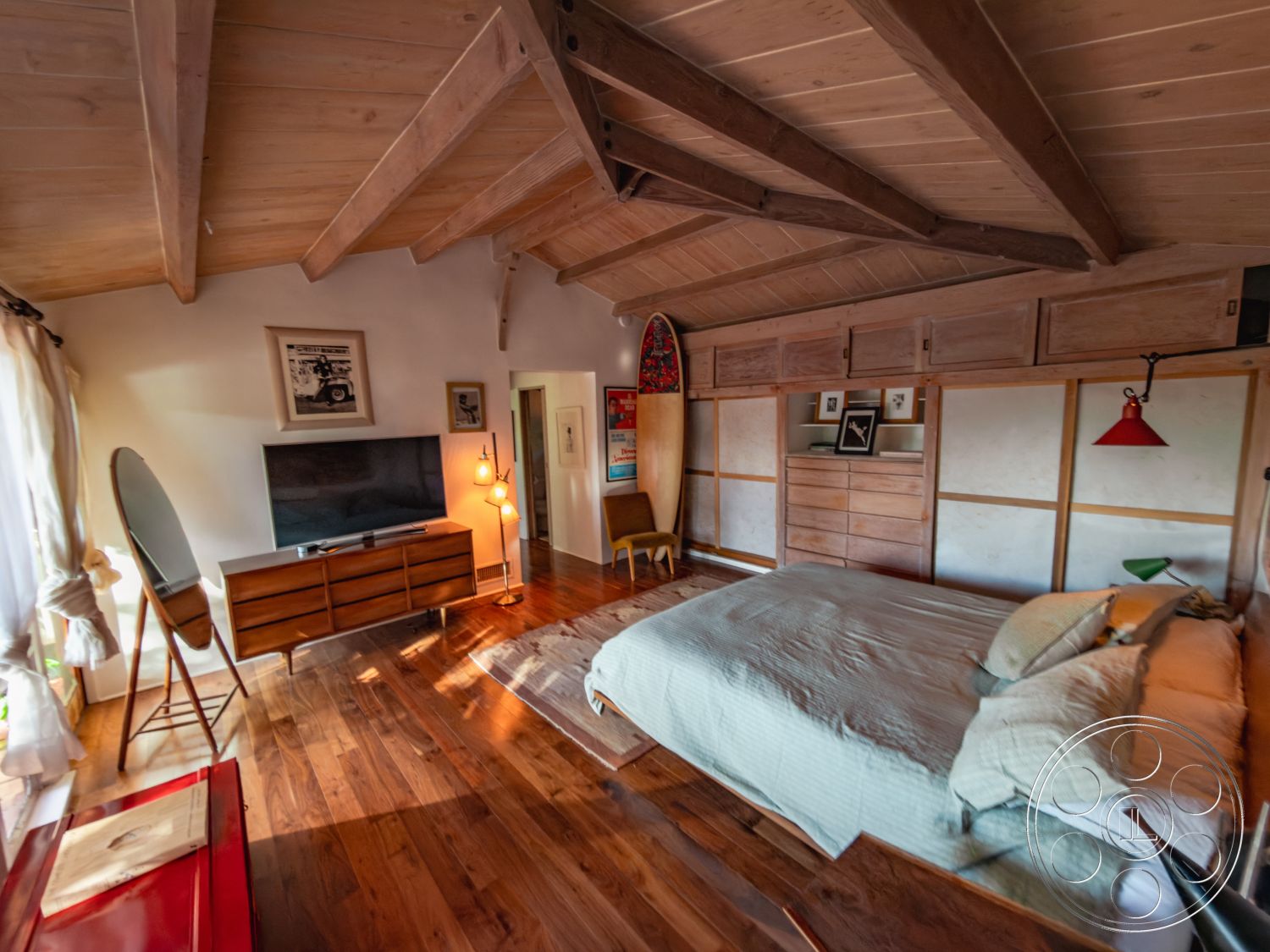 Pad 90210 - natural light from windows, textured wall treatment, rustic decor elements, sliding closet doors, exposed wood ceiling beams, hardwood bedroom floors, white painted walls, minimalist furniture design, built-in wooden cabinets, open layout bedroom, modern flat-screen TV setup, red accent lighting fixture, beach house interior, creative wall art displays, cozy bedding design