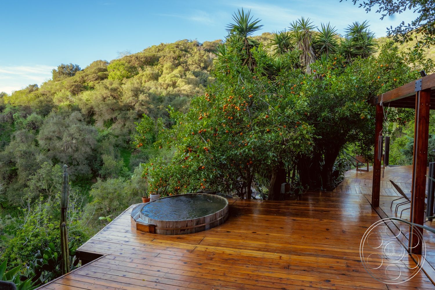 Pad 90210 - outdoor relaxation area, wooden lounge chairs, natural landscape view, surrounding lush greenery, exterior wooden deck flooring, natural hillside setting, integrated into nature, round wooden hot tub, rustic outdoor design, panoramic mountain backdrop