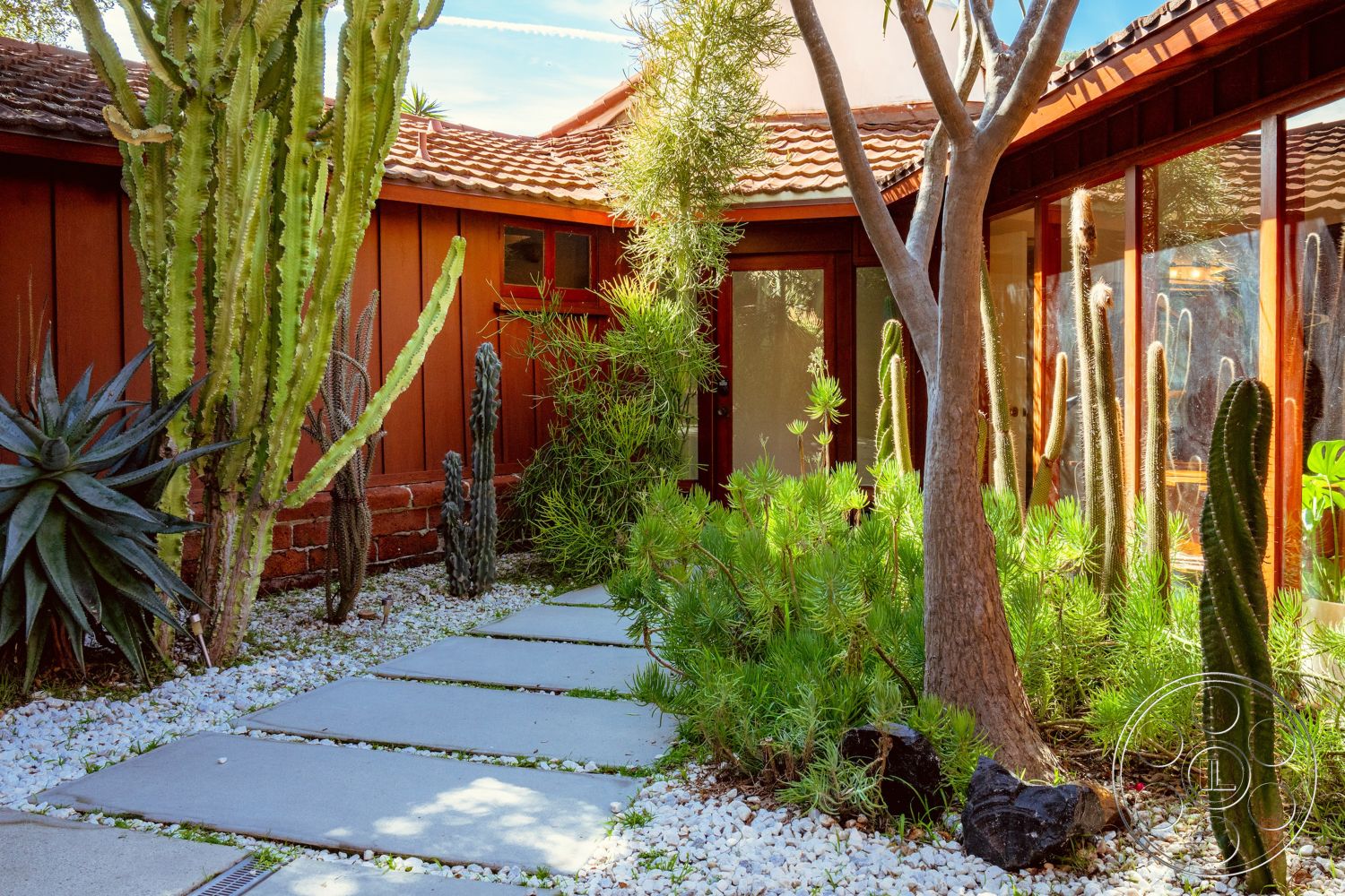 Pad 90210 - exterior, modern architecture, minimalist design, glass sliding doors, outdoor seating area, wooden beams, tropical plants, floor-to-ceiling windows, brick accent wall, curved walkway, desert landscaping, sunny courtyard, tile roof, cactus garden, sculptural plants, redwood siding, natural stone ground cover, stepped concrete pathway