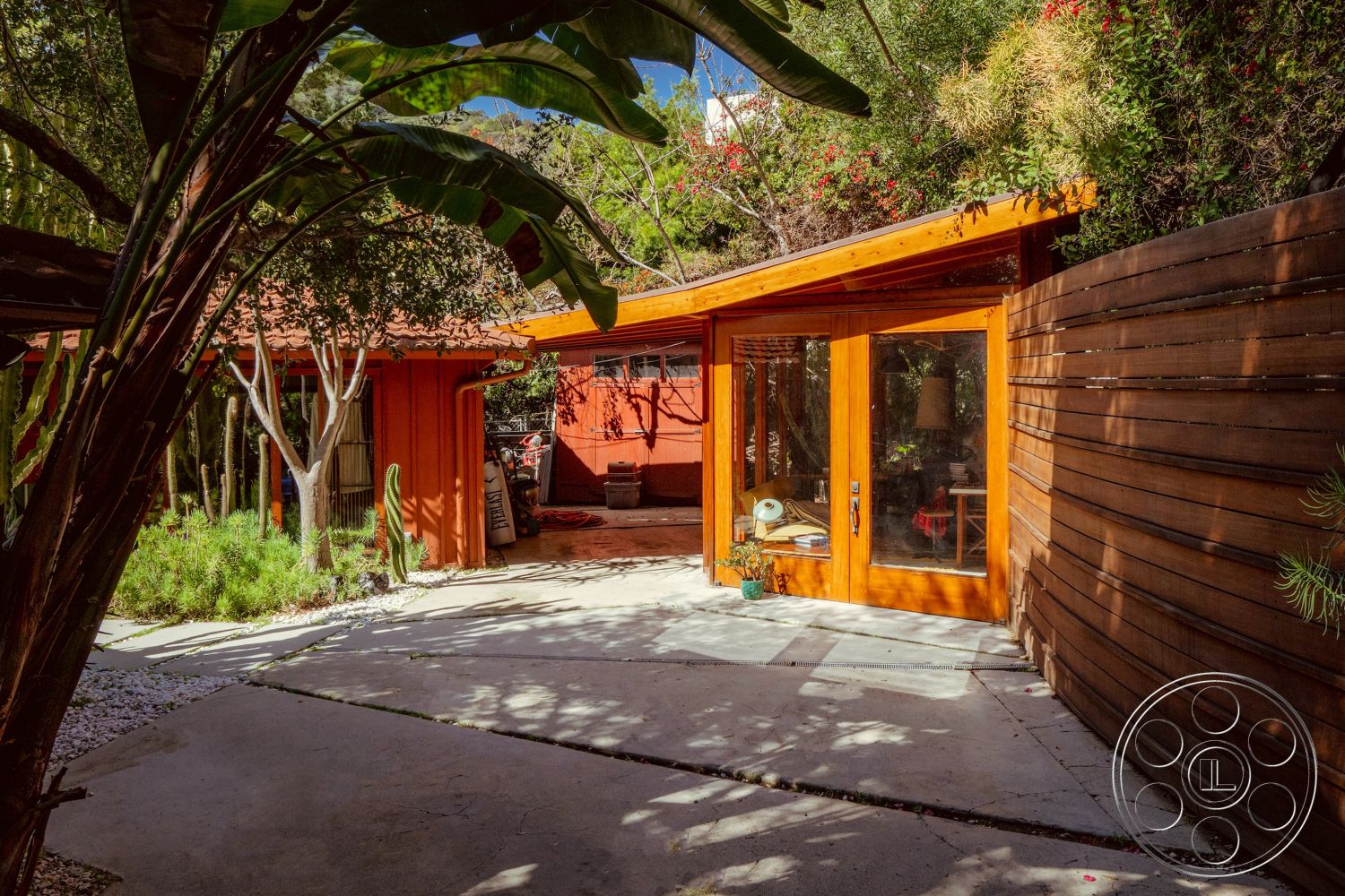 Pad 90210 - exterior, modern design elements, red stucco walls, natural stone pathway, landscaped garden area, concrete patio flooring, rustic outdoor decor, natural light-filled space, wood beam ceiling, sloped roof design, urban garden setting, lush greenery surrounding, mid-century modern influence, framed glass doors, desert plants landscaping, wood siding walls, open courtyard space, textured retaining wall, eclectic outdoor lighting, horizontal wood slat fence