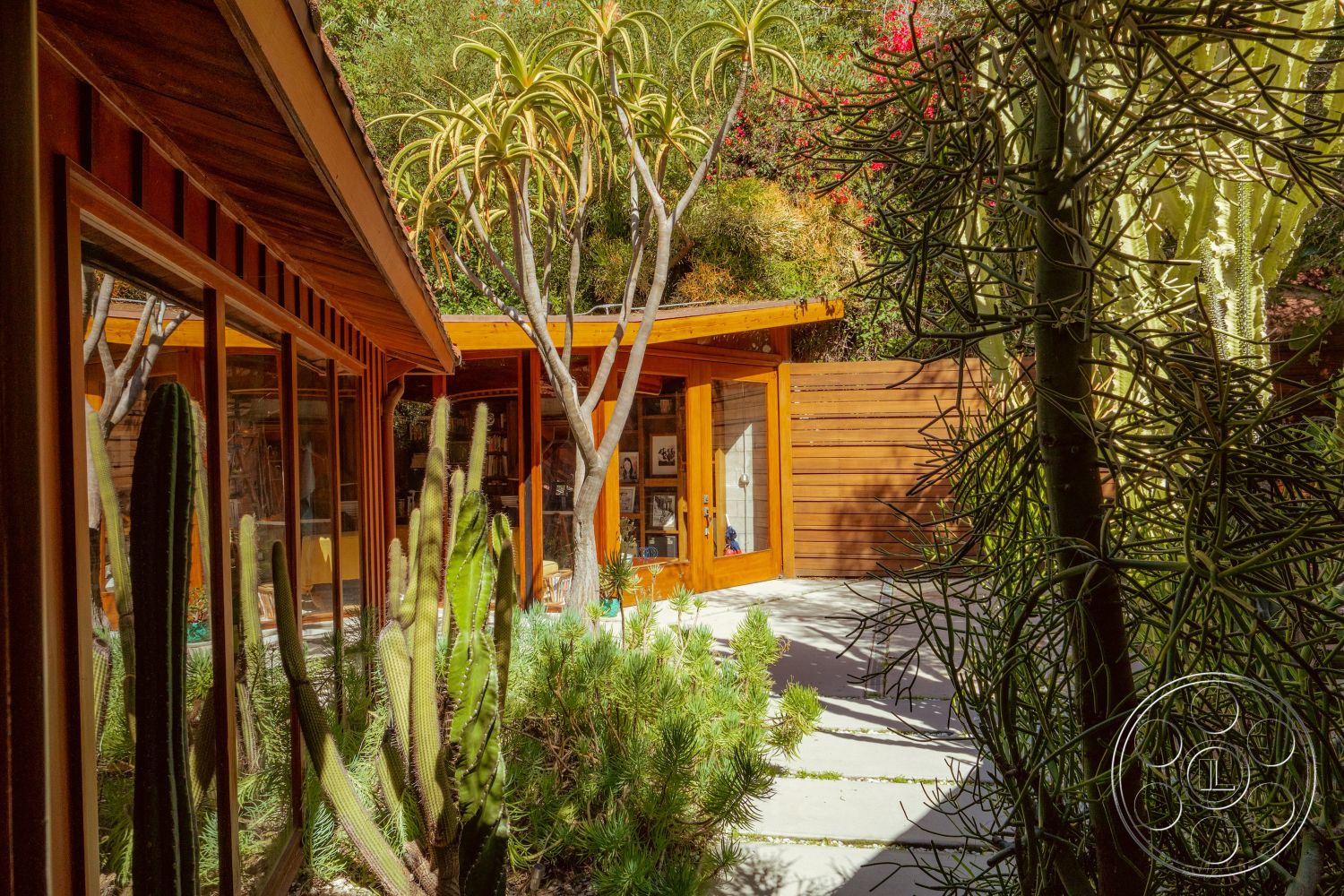 Pad 90210 - glass sliding doors, exposed wooden beams, modern landscaping, open-air courtyard, sustainable design elements, concrete patio flooring, casual outdoor seating area, minimalist architectural style, integrated indoor-outdoor living, natural light-filled interior, wooden exterior wall panels, flat-roof design, desert garden with cacti, poured concrete pathways, surrounding desert vegetation