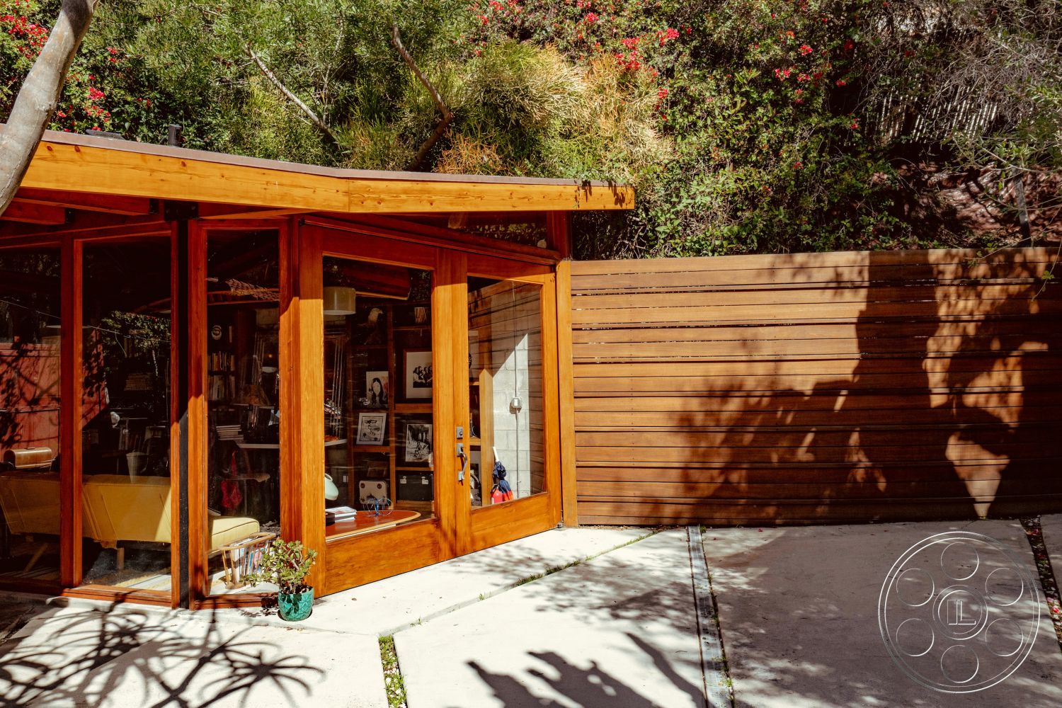 Pad 90210 - concrete walkway, exposed structural elements, urban hillside location, lush garden setting, interior open floor plan, interior wood beam ceiling, contemporary design aesthetics, integrated indoor-outdoor living, modern flat roof design, glass partition wall, exterior glass window panels, exterior wooden wall cladding, natural light infused interior, exterior concrete patio surface, curved roofline structure, interior glass door entryway, exterior modular garden wall, decorative exterior landscaping, wooden framed windows