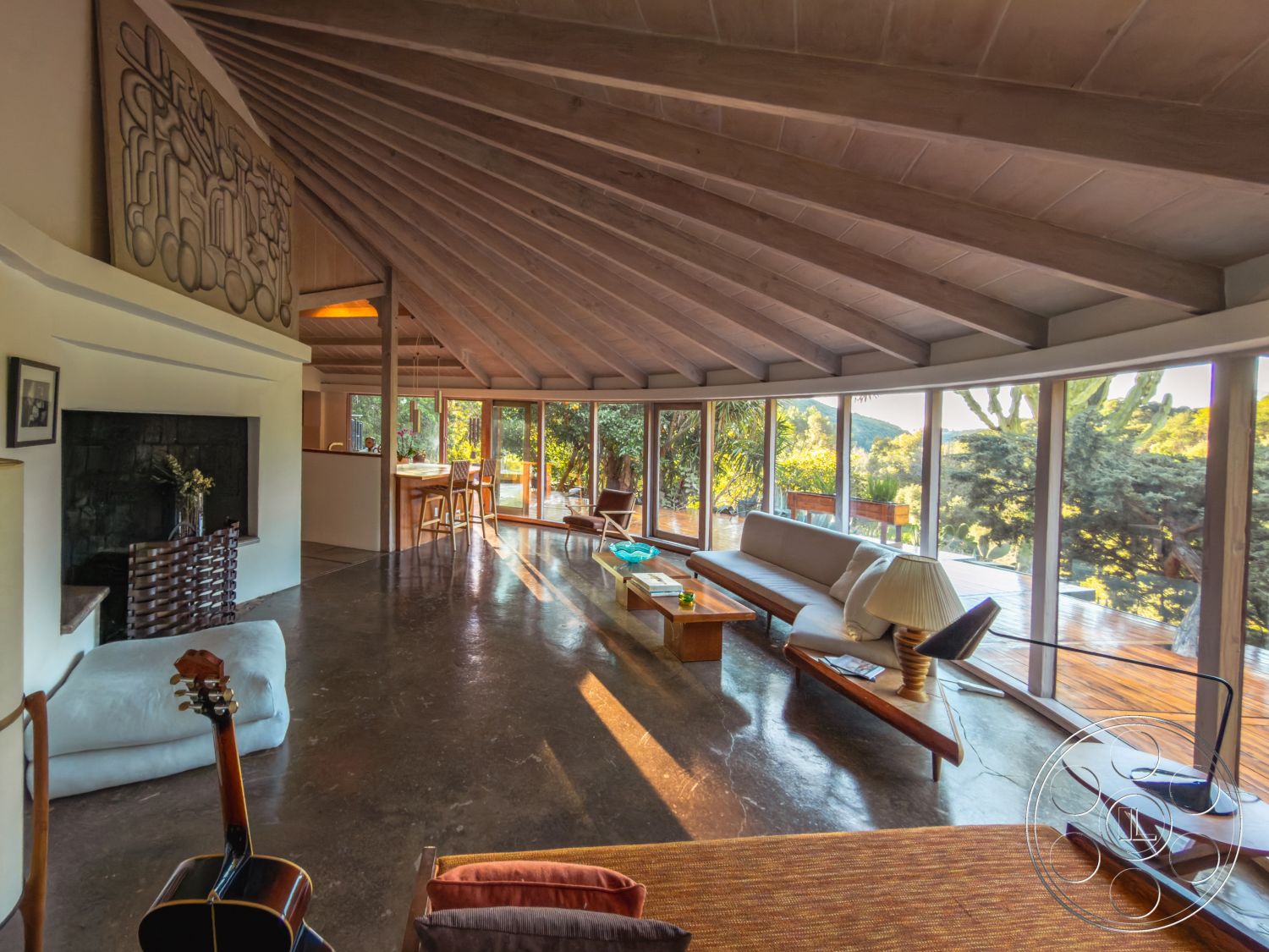 Pad 90210 - polished concrete flooring, wooden dining table, garden view, interior living space, white painted walls, open concept living area, exposed wood beam ceiling, ranch-style home, floor-to-ceiling glass windows, outdoor patio access, modern minimalist furniture, natural light-filled interior, stone fireplace feature wall, sloped wooden ceiling beams, vintage-style lounge chair