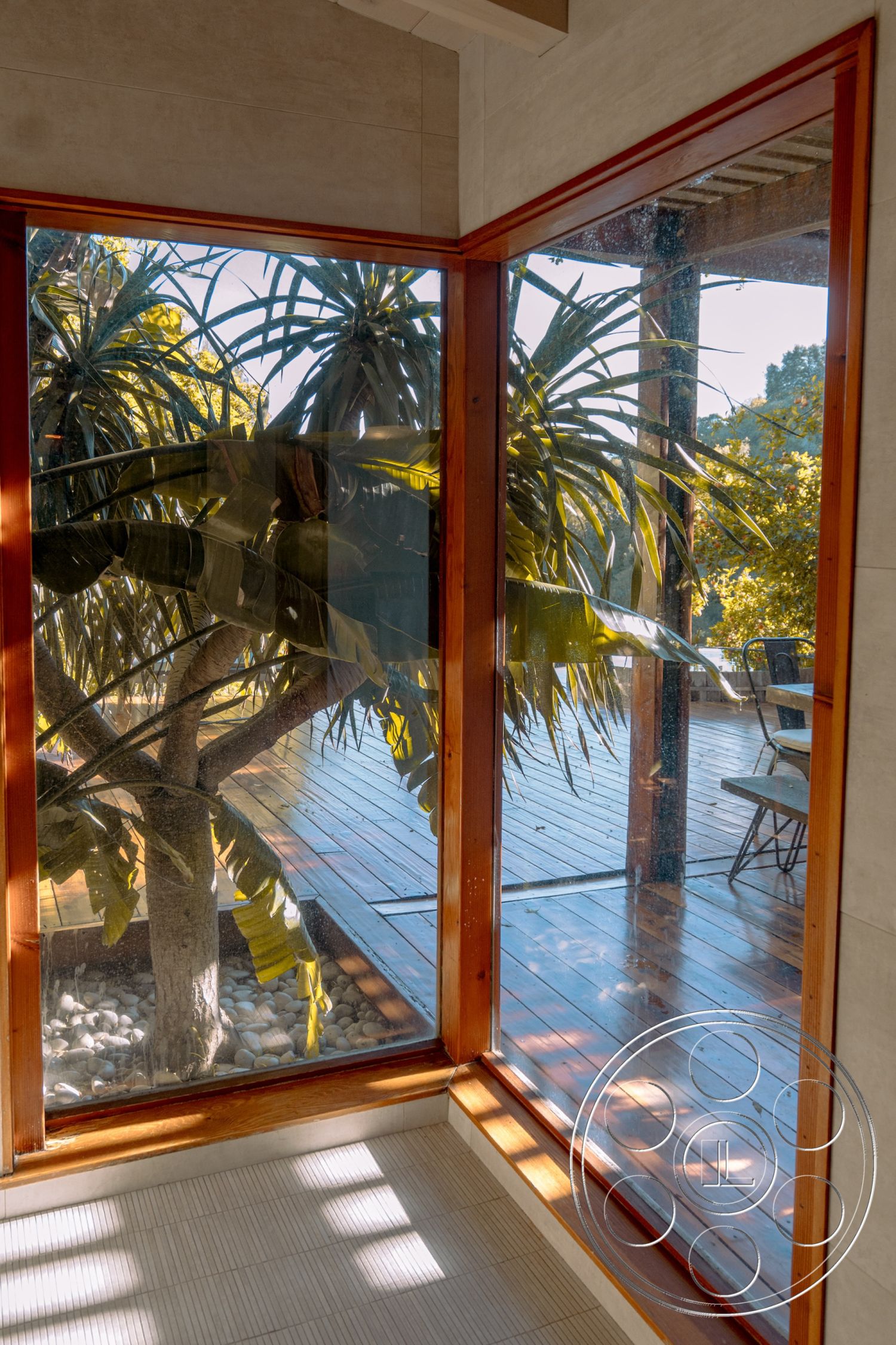 Pad 90210 - interior natural light, exterior landscaped garden, exterior wooden deck, interior minimalist design, interior floor-to-ceiling glass windows, exterior outdoor dining area, interior wooden window frames, interior stone pebble flooring, interior tiled wall treatments, interior bamboo window coverings, exterior tropical plant view, exterior open deck space, exterior light wood construction, interior vibrant green foliage, interior decorative gravel base