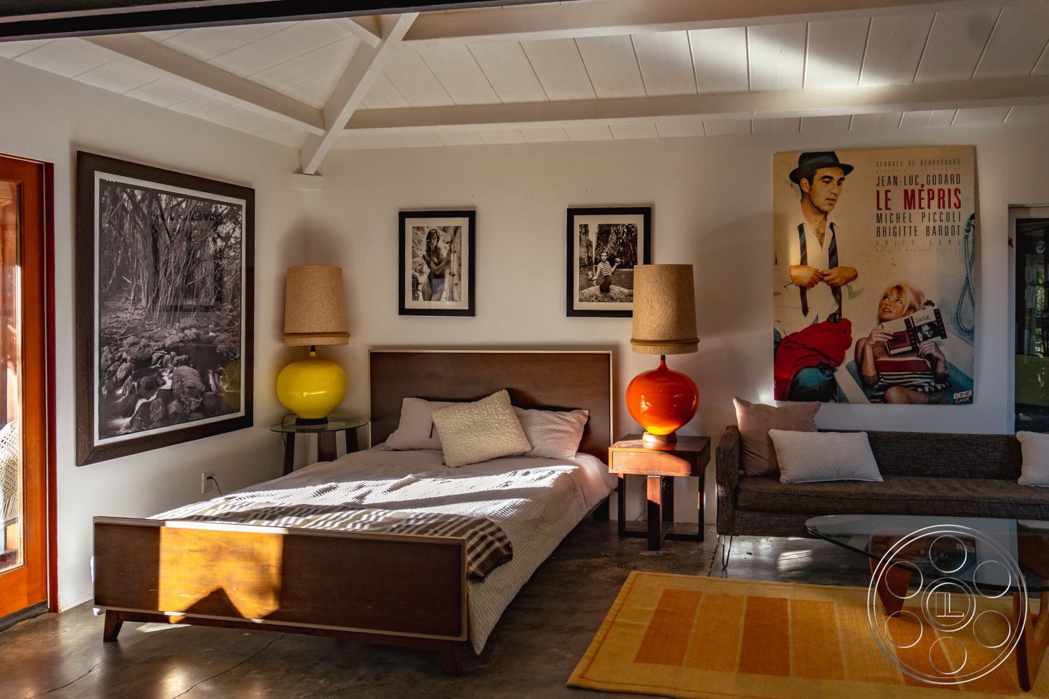 Pad 90210 - exposed wood ceiling beams, interior, concrete living room floor, interior, mid-century modern bedroom design, interior, wooden bed frame with light bedding, interior, vintage movie poster wall art, interior, abstract photography wall decor, interior, yellow ceramic table lamp, interior, brown upholstered sofa with cushions, interior, glass coffee table, interior, textured area rug with geometric design, interior, wooden framed windows with natural light, interior, orange accent chair, interior, open floor plan layout, interior, multi-functional living space, interior