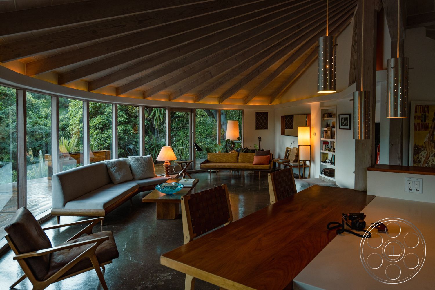 Pad 90210 - indirect lighting, circular coffee table, mid-century modern design, exposed wood ceiling beams, interior living room, open concept living area, integrated seating area, stylish pendant lighting, integrated shelving units, modern accent chairs, tropical garden view, concrete floor with polished finish, curved glass walls, outdoor deck view, wooden furniture with natural finish, varied seating arrangements