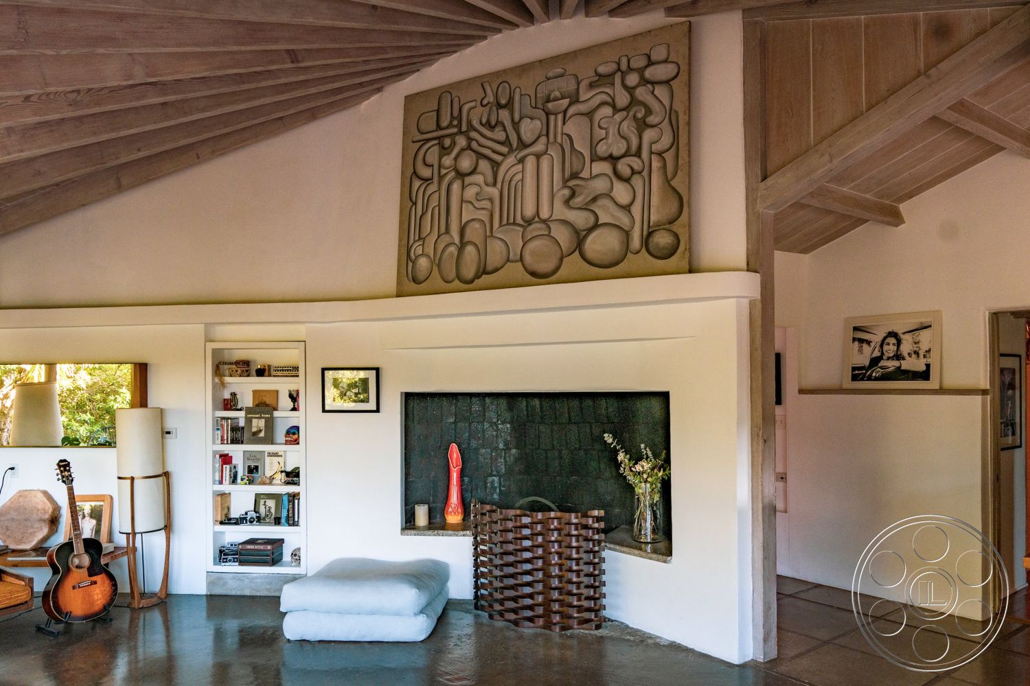 Pad 90210 - textured plaster wall interior, exposed wood ceiling beams interior, modern minimalist decor interior, concrete floor interior, warm color palette interior, open floor plan living area interior, stone fireplace wall interior, built-in bookshelves interior, large windows with garden view interior, abstract wall art interior, natural light flowing in interior, wooden furniture interior, relaxed seating area interior, artistic decor elements interior, unique sculptural details interior