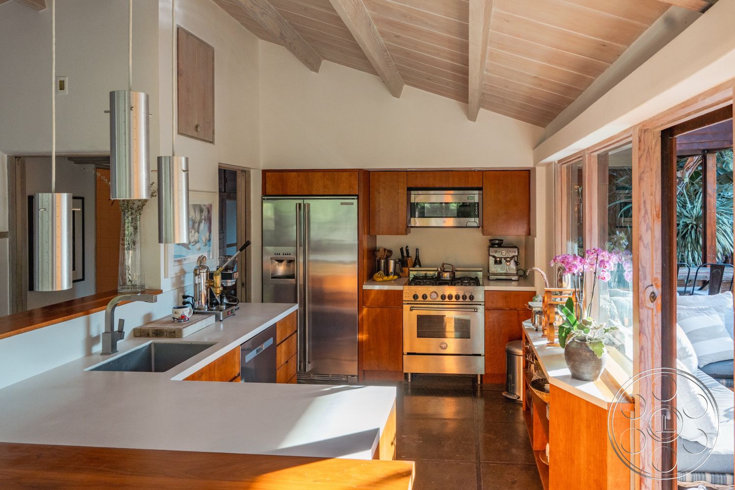 Pad 90210 - neutral color palette, natural light, contemporary style, minimalist design, stainless steel appliances, open concept layout, modern farmhouse aesthetic, pendant lighting fixtures, slate tile flooring, exposed wood ceiling beams, built-in kitchen cabinets, interior kitchen with wood cabinetry, kitchen island with seating, large windows with wooden frames, white concrete countertops