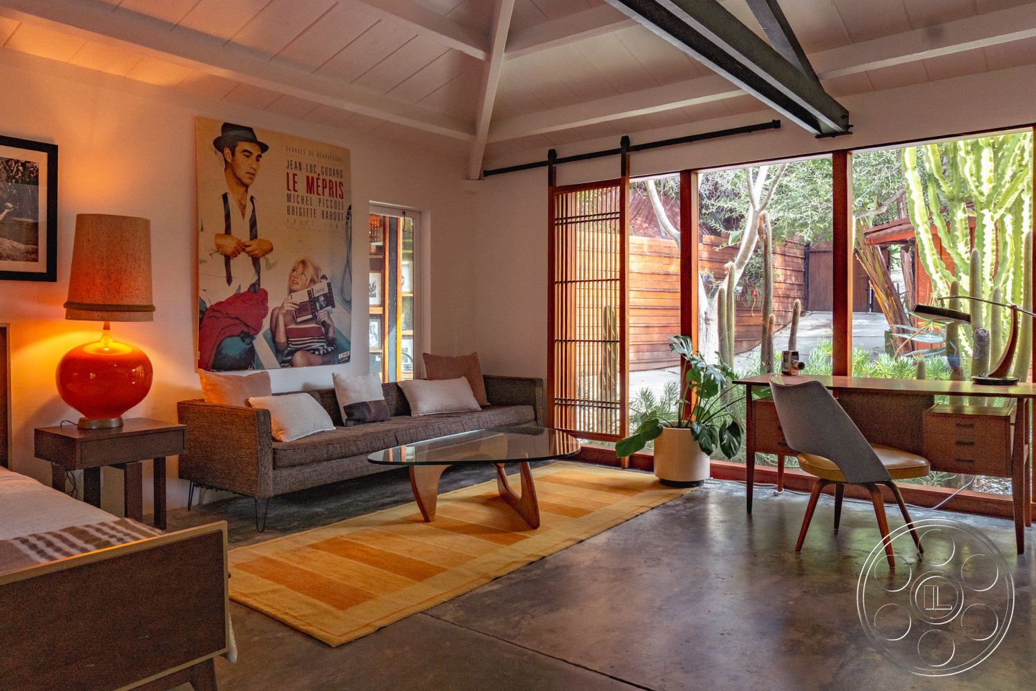 Pad 90210 - minimalist decor, textured accent wall, natural light from large windows, woven area rug, contemporary coffee table, urban garden view, exposed wood ceiling beams, concrete floor finish, built-in shelving unit, indoor plant accents, glass wall panels, open concept interior, wooden sliding door, modern upholstered sofa, vintage poster wall art, mid-century inspired chair, casual living room design, retro-style lamp