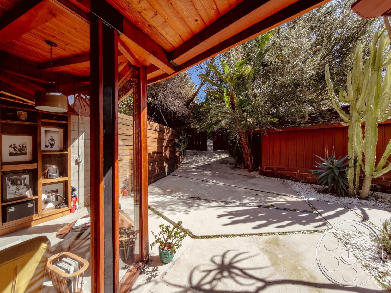 Pad 90210 - interior natural light, interior minimalistic design, exterior sliding glass door, exterior shaded seating area, exterior landscaped garden, interior glass walls, exterior concrete pathway, interior modern furniture, interior warm wood tones, exterior low-maintenance plants, exterior wooden fence panels, exterior exposed wooden roof beams, exterior desert landscaping features, interior wooden shelving unit, interior hardwood accent wall, exterior stone gravel bed, exterior desert cactus, exterior rustic shed, interior contemporary art displays, exterior partitioned spaces