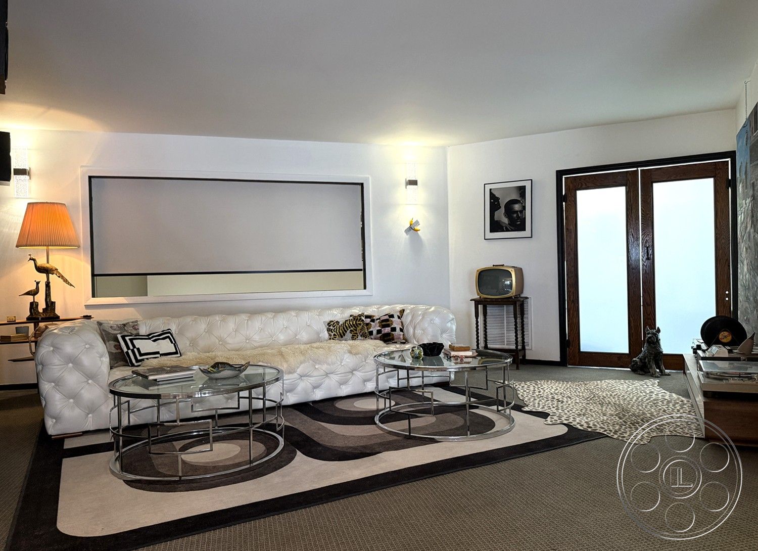 Studio 45 - glass coffee table, neutral wall color, textured wall paneling, contemporary aesthetic, multicolored area rug, decorative table lamp, retro decor elements, interior living room, dark wood front door, modern artwork on walls, white tufted leather sectional sofa, vintage television stand, geometric patterned carpet, exposed ceiling light fixtures