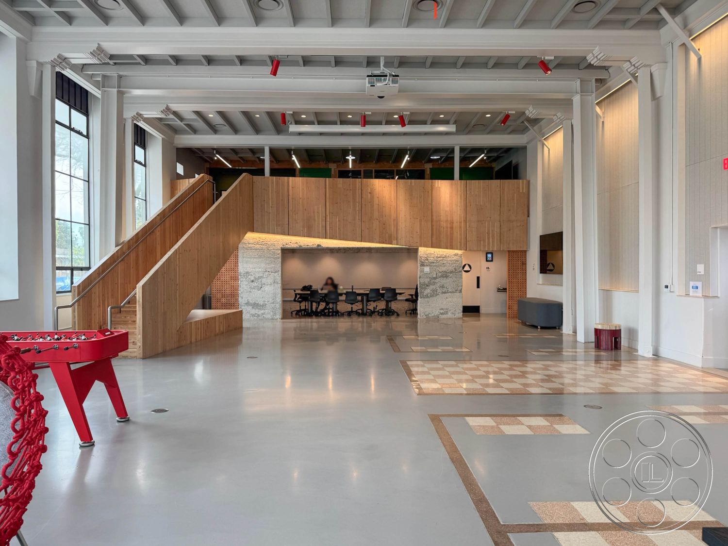 Studio 101 - exposed wood ceiling beams, interior, concrete flooring, polished concrete floor, interior, wooden staircase, angled wooden stairs, interior, brick wall, rustic brick accent wall, interior, glass windows, large industrial-style windows, interior, modular office area, contemporary office space, interior, textured wall panels, wooden wall paneling, interior, red accent furniture, modern red game table, interior, geometric tile patterns, checkered tile floor design, interior, open floor plan, spacious communal area, interior, modern finishes, contemporary design elements, interior, functional lighting, sleek recessed lighting, interior, creative workspace, collaborative meeting area, interior