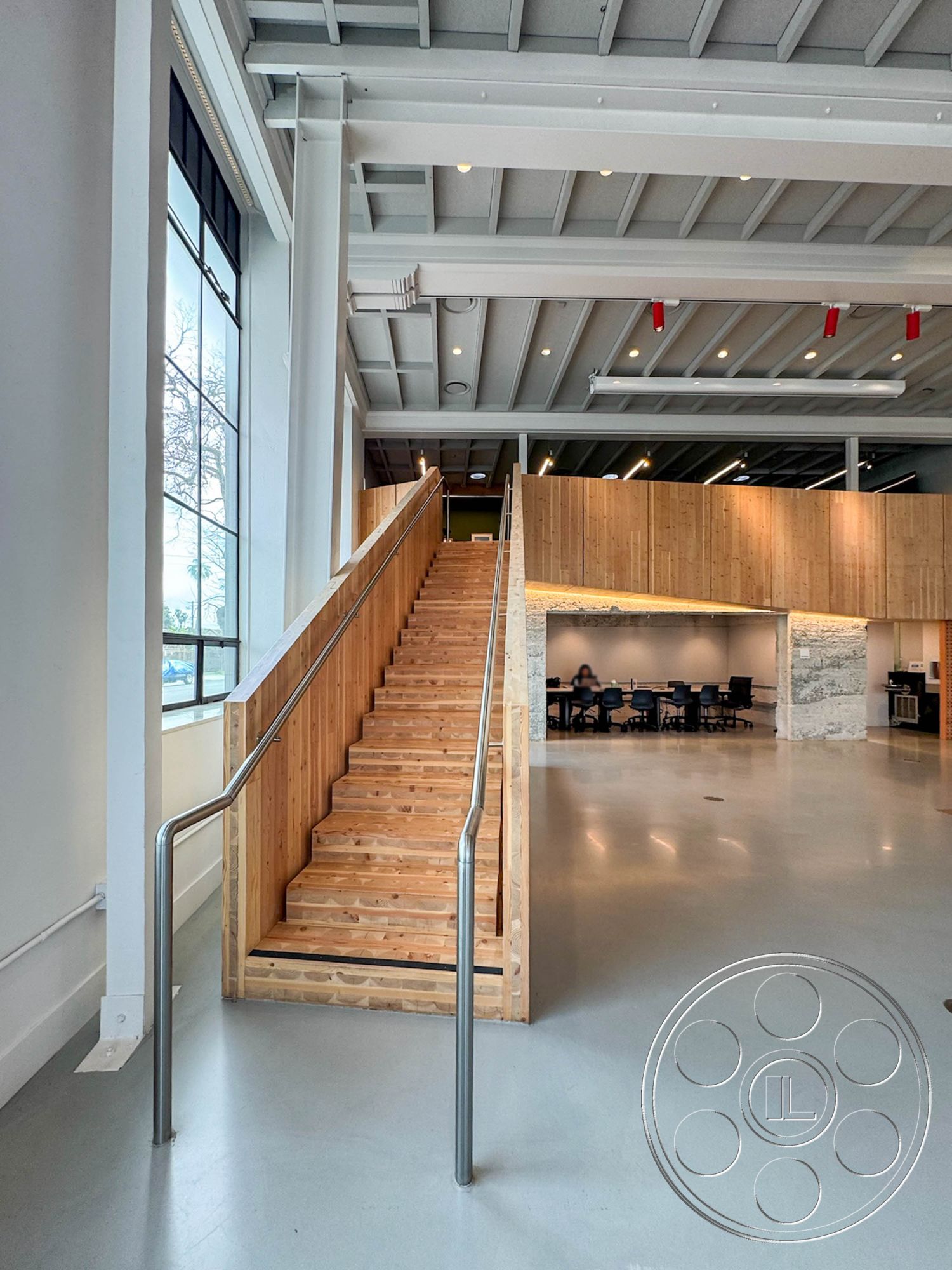 Studio 101 - neutral color palette, large windows, exterior, minimalist design, concrete floor, wooden staircase, open concept space, exposed wood ceiling beams, modern interior design, natural light interior, functional meeting space, steel stair railings, wood paneling wall, industrial architectural style, flush-mounted ceiling lights, smooth surface flooring