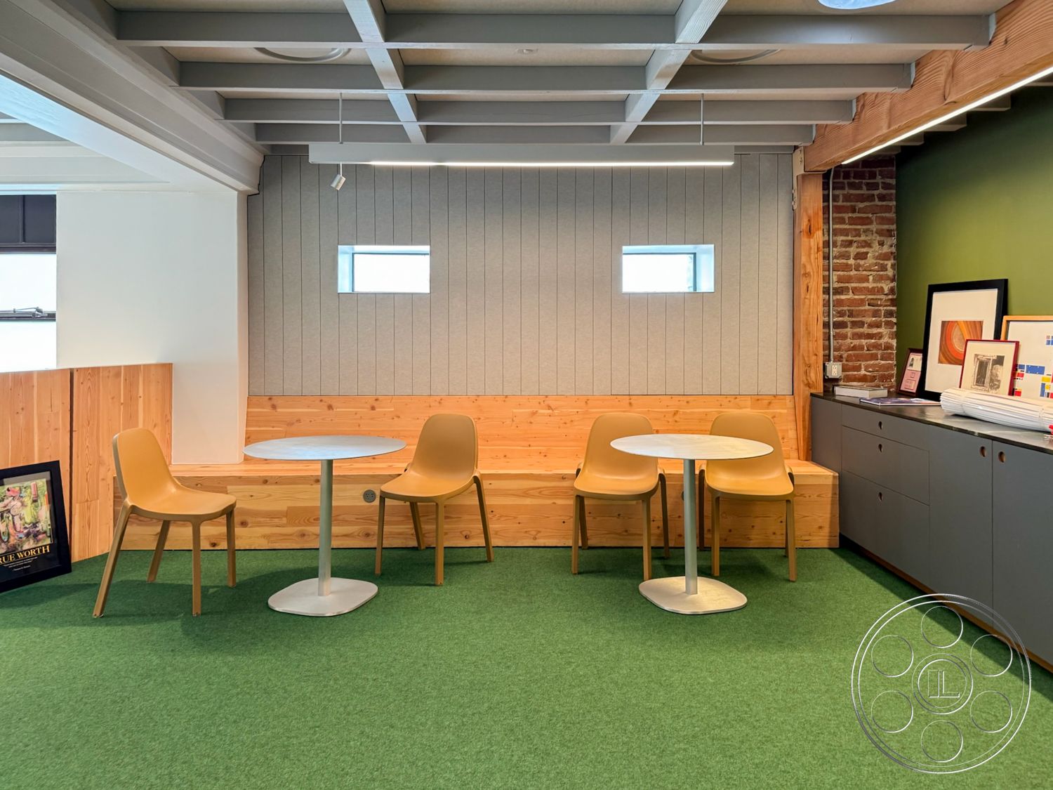 Studio 101 - exposed wood ceiling beams interior, green carpet flooring interior, brick accent wall interior, gray fabric wall panels interior, wood planked bench interior, minimalist circular table interior, modern ergonomic chairs interior, painted accent wall interior, flat-panel cabinetry interior, natural light through small windows interior