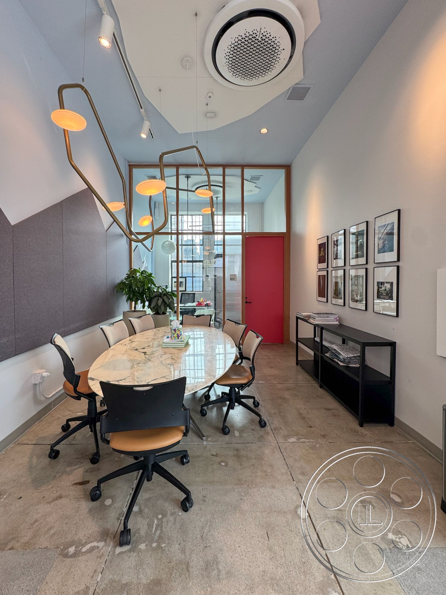 Studio 101 - modern pendant lighting, exposed concrete floor, green indoor plant, interior office space, glass partition wall, framed art wall decor, oval marble conference table, black swivel office chairs, sloped ceiling with recessed lighting, red accent door, acoustic wall paneling