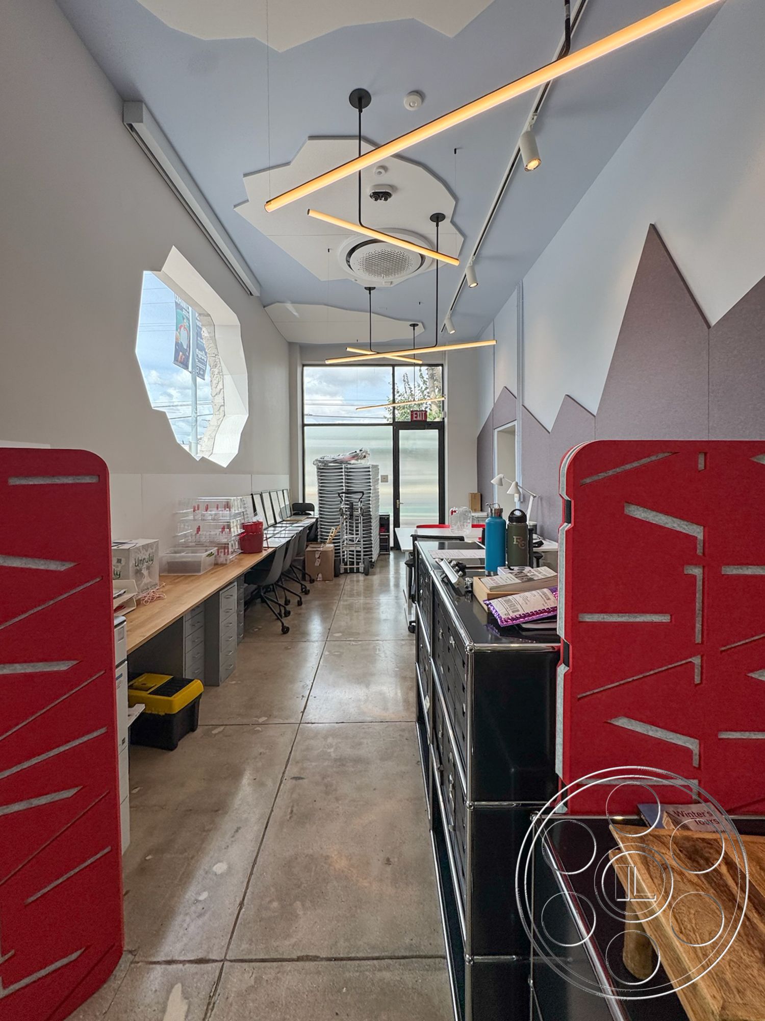 Studio 101 - minimalist aesthetic, modern furniture, functional workspace, workspace area, natural light emphasis, commercial interior design, urban office setting, open layout space, modern industrial style, concrete flooring interior, dynamic spatial arrangement, LED linear lighting fixtures, exposed concrete wall accent, wood office desk surface, metal drawer units, geometric ceiling details, oval-shaped ceiling recess, large glass storefront window, red colored partition walls