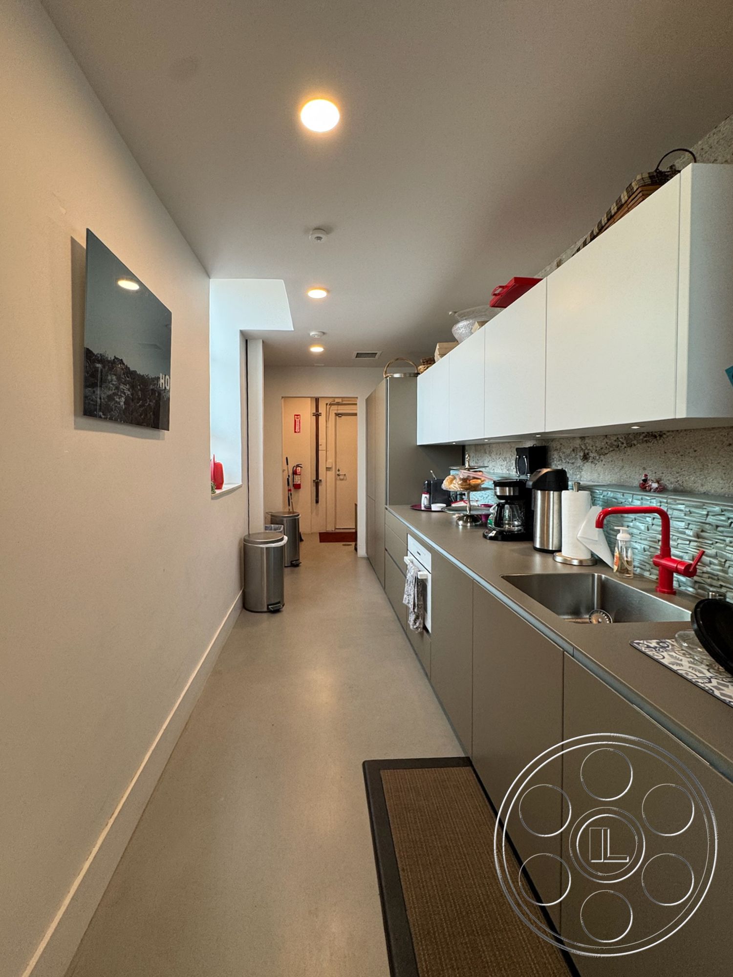 Studio 101 - modern cabinetry, textured plaster walls, open concept kitchen, minimalist interior design, white painted walls, LED recessed lighting, stainless steel kitchen sink, concrete kitchen floors, glass tile kitchen backsplash, pedestrian entry hallway, red pull-down kitchen faucet, marble countertop accents, long narrow kitchen layout, high-efficiency appliances