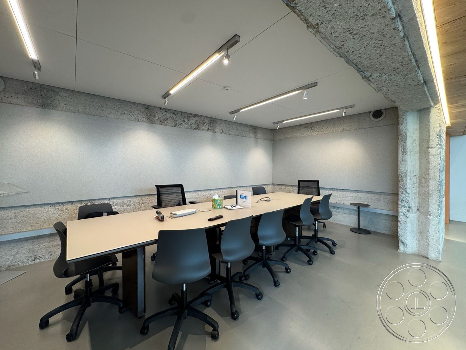 Studio 101 - minimalist decor, smooth concrete flooring, textured plaster wall, glass partition wall, modern office furniture, rectangular conference table, exposed concrete columns, interior conference room, acoustic panel wall treatment, LED overhead lighting, concrete wall treatments, lightweight black swivel chairs, soft grey color palette