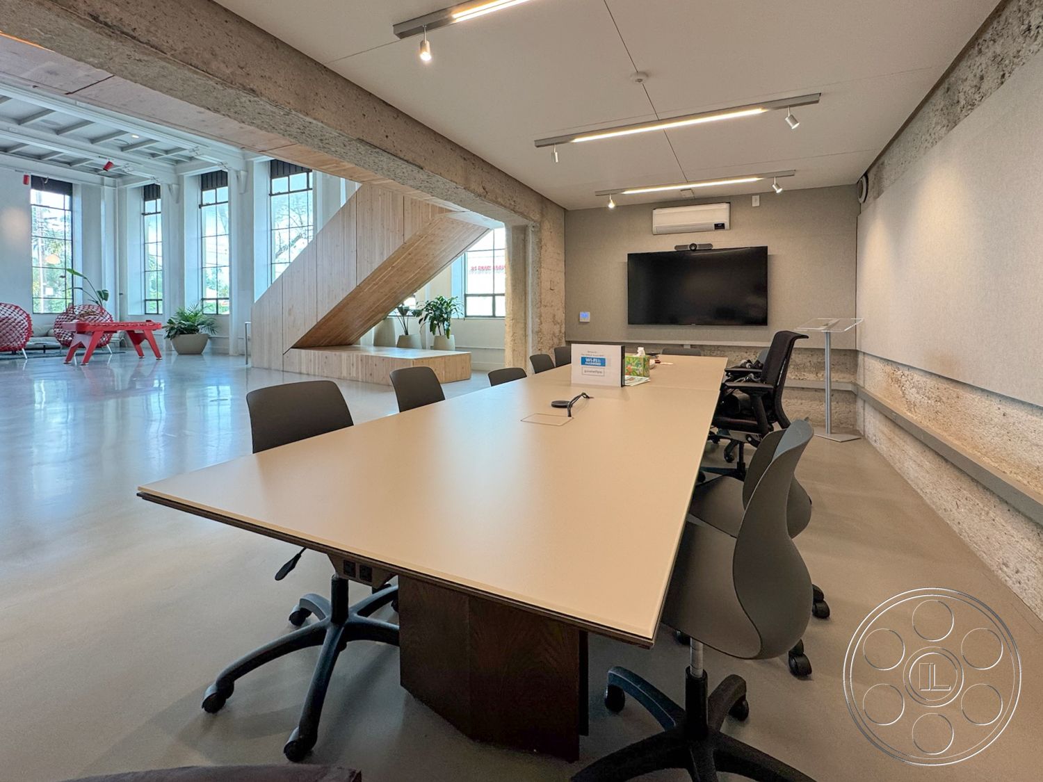 Studio 101 - concrete flooring, minimalist design elements, exposed concrete walls, floor-to-ceiling windows, soft natural lighting, collaborative work area, contemporary office space, wood beam ceiling details, modern conference table, urban interior setting, sleek ergonomic chairs, wooden staircase with open treads, gray felt wall paneling