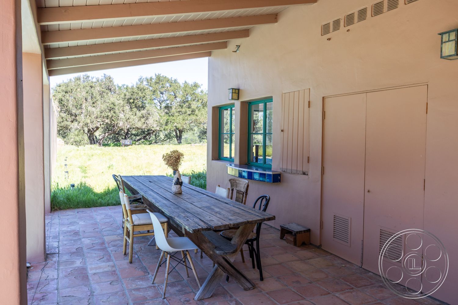 Casa del Rey - natural light, al fresco dining area, open outdoor space, terracotta tile flooring, green window frames, desert setting, eight-person dining table, natural landscape view, wood beam ceiling, exterior patio area, painted stucco walls, mixed seating chairs, rustic wooden table