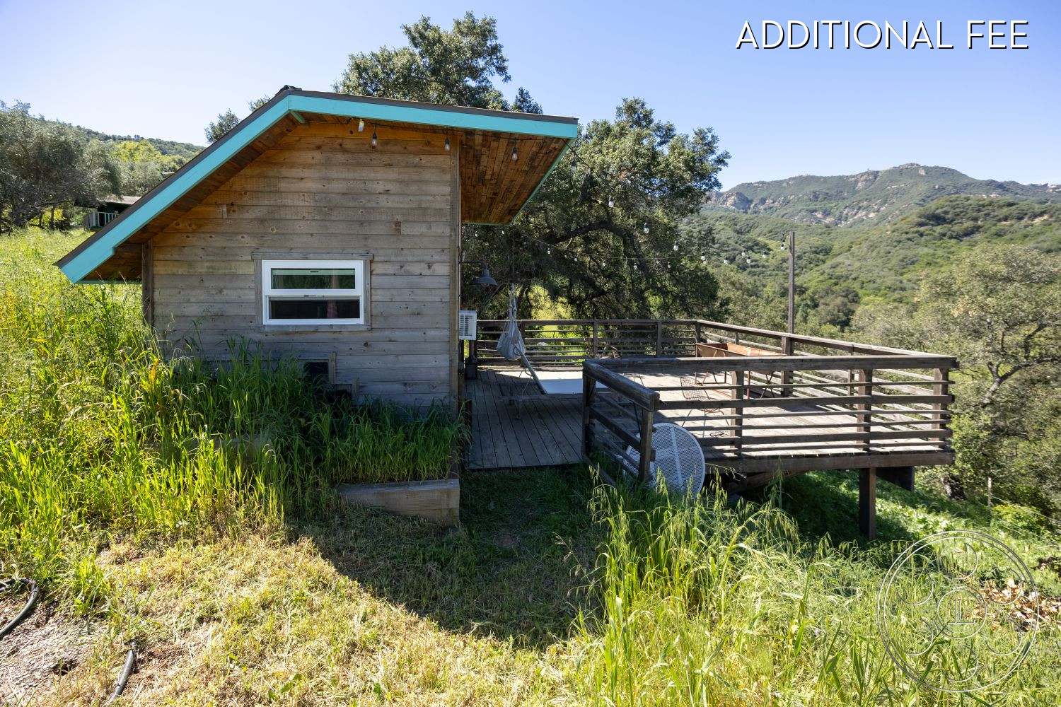 Casa del Rey - outdoor seating area, natural wood finishes, mountain view setting, large windows for natural light, flat roof with overhang, wooden deck flooring, rustic cabin style, eco-friendly construction, exterior wooden siding, sloped terrain landscaping, deck patio with wooden railings, grass-covered garden area, open deck for relaxation, semifunctional outdoor space