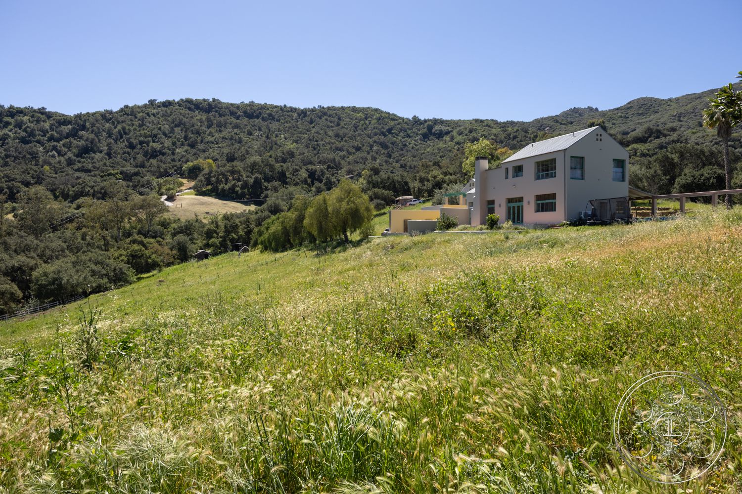 Casa del Rey - natural habitat, open landscape, sloped lawn, mountain view setting, white painted walls, surrounded by lush greenery, sustainable home design, two-story modern home, exterior house with gable roof, large windows with green trim