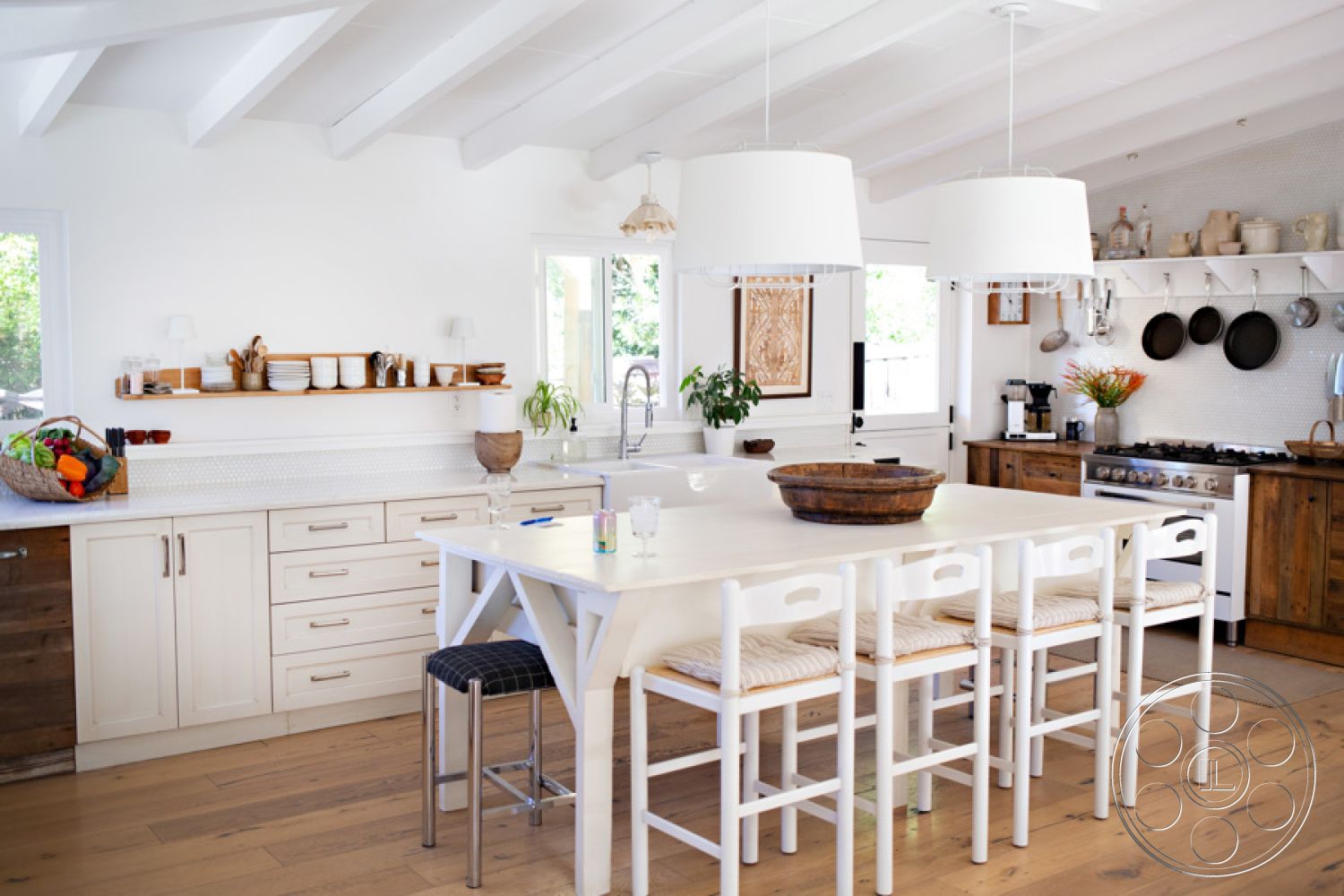 Ranch 33 - exposed wood beam ceiling, stainless steel kitchen appliances, modern pendant lighting fixtures, white quartz kitchen countertop, interior kitchen cabinetry with wood paneling, polished hardwood kitchen flooring, open-plan living space with natural light, shiplap accent wall behind kitchen dining area, minimalist kitchen design with functional shelving, farmhouse-style dining table with bowl centerpiece, elegant bar stools with woven seats, textured wallpaper behind dining area, white modern cabinetry with brushed nickel hardware, geometric wall-mounted storage, neutral color palette with natural materials