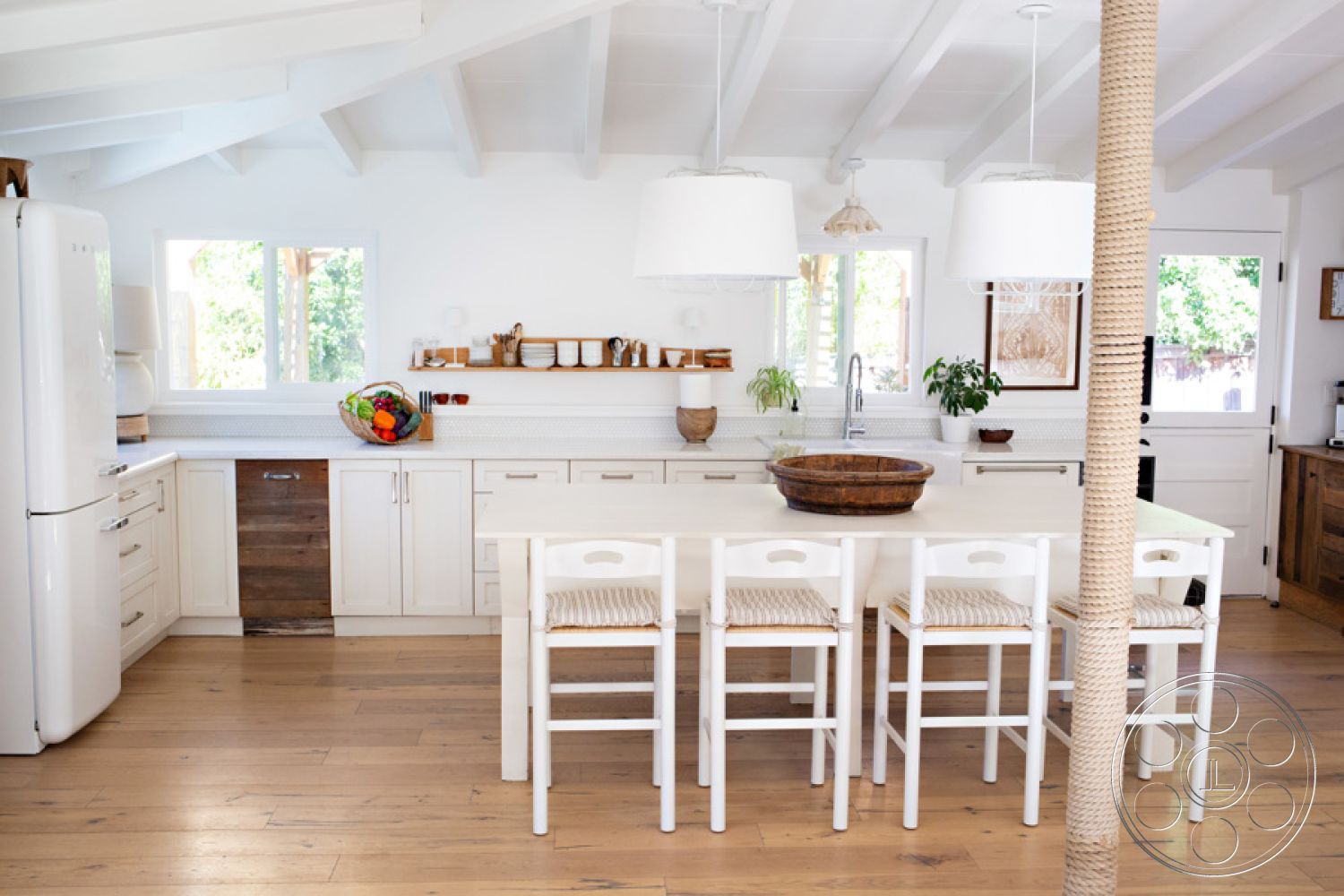 Ranch 33 - textured wall paneling, stainless steel refrigerator, interior kitchen, minimalist kitchen design, open floor plan layout, hardwood kitchen flooring, exposed wood beam ceiling, glass window views, white shaker kitchen cabinets, marble countertop kitchen island, white pendant lighting fixtures, rustic wooden bowl centerpiece, natural light kitchen space, cozy breakfast bar seating, decorative wall shelf with dishware, plant accents in kitchen decor