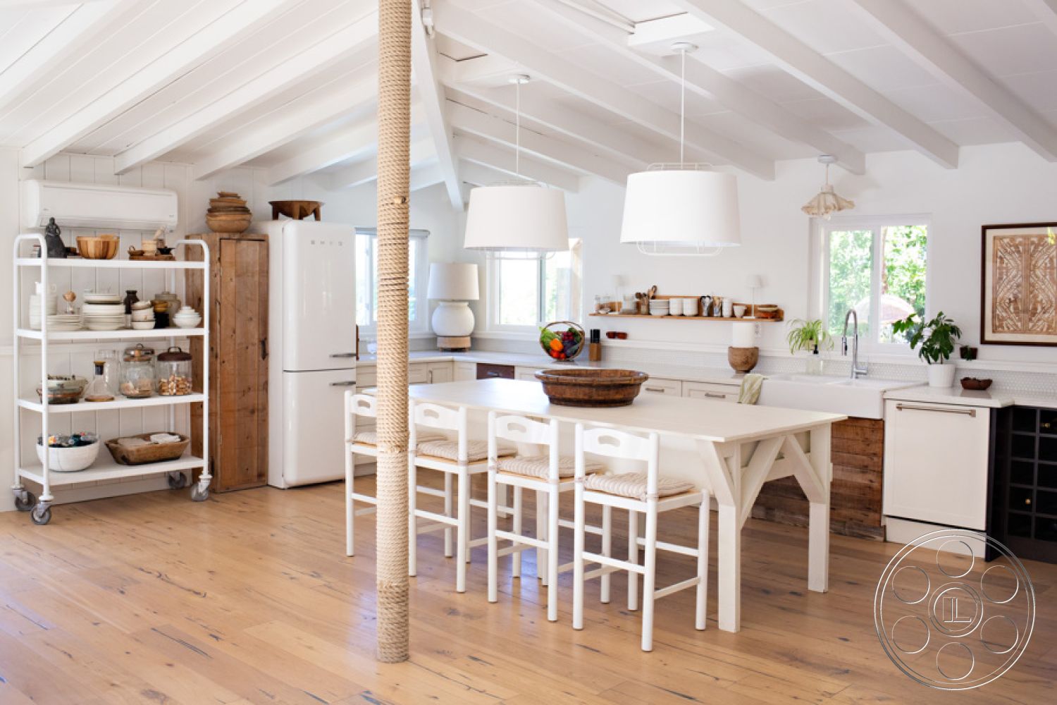 Ranch 33 - neutral color palette interior, exposed wood ceiling beams interior, white painted walls interior, modern farmhouse style interior, textured wall treatment interior, hardwood kitchen flooring interior, open concept chef's kitchen interior, glass kitchen windows interior, white pendant lighting interior, rustic wooden kitchen shelves interior, stone countertop kitchen island interior, woven fabric dining chairs interior, beach house decor interior, functional kitchen workspace interior, natural light-filled kitchen interior, kitchen island with built-in storage interior, light wood cabinetry interior, circular dining table setting interior, spacious kitchen layout interior